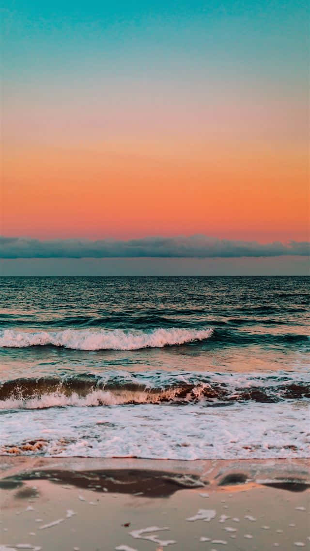 Cute Beach iPhone 桌布 壁紙 — 海浪拍打濕沙，天空呈現橙、粉紅和藍綠色的鮮豔日落色彩。