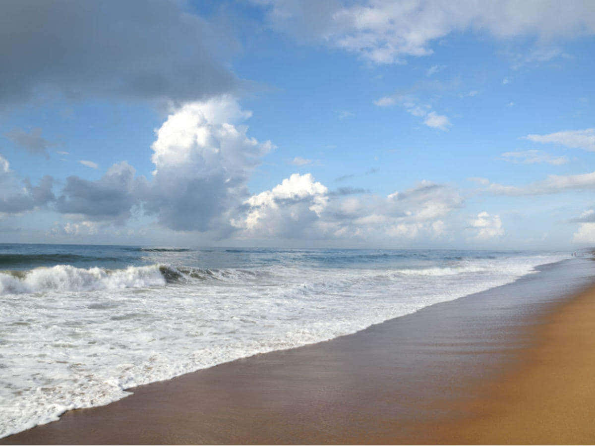Sea Beach 桌布 壁紙 — 海浪拍打金色沙灘，廣闊天空下戲劇性的蓬鬆雲朵。