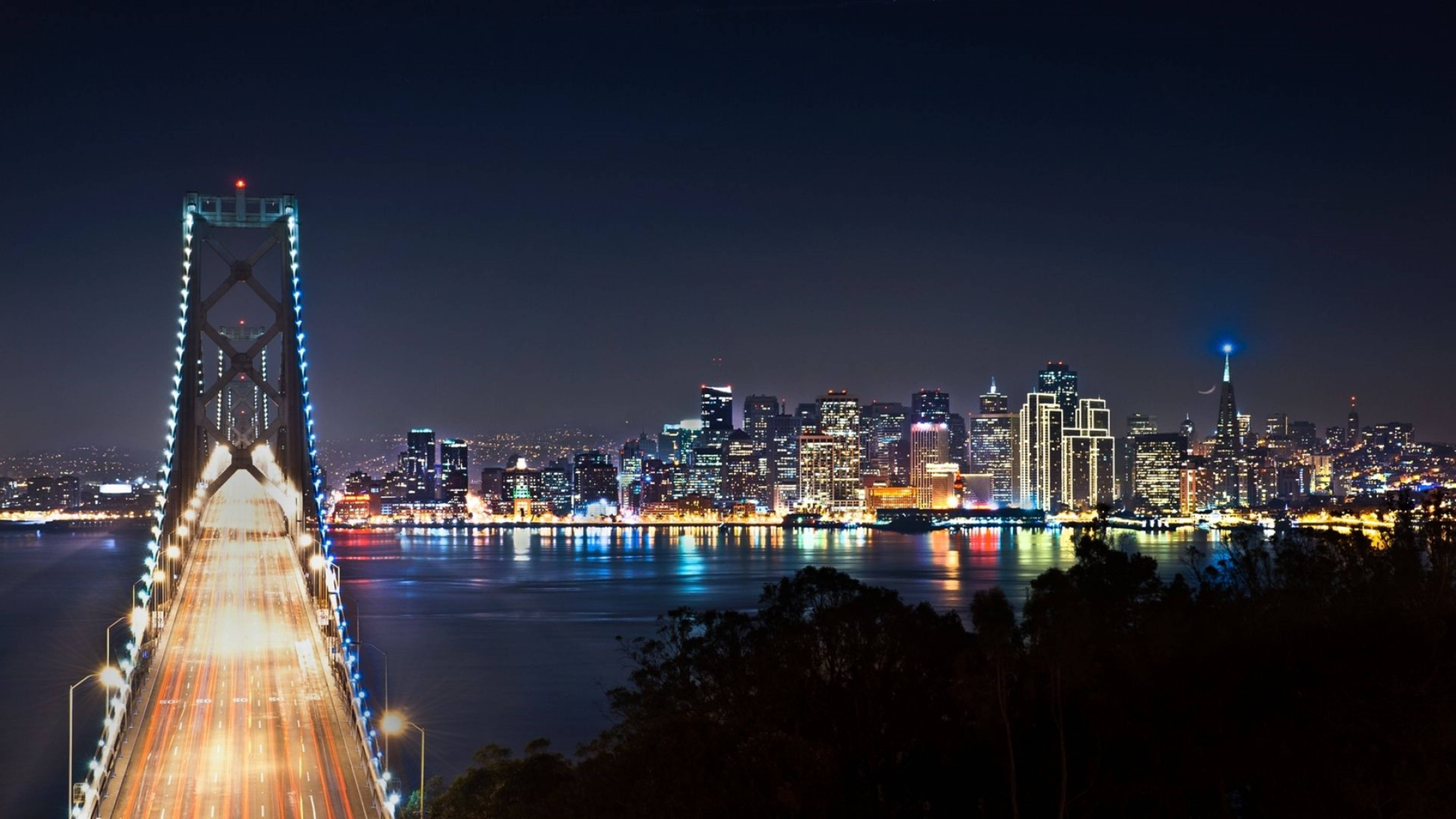 風景動畫 桌布 壁紙 — 海灣大橋和舊金山天際線的迷人夜景，璀璨的城市燈光倒映在水面上。