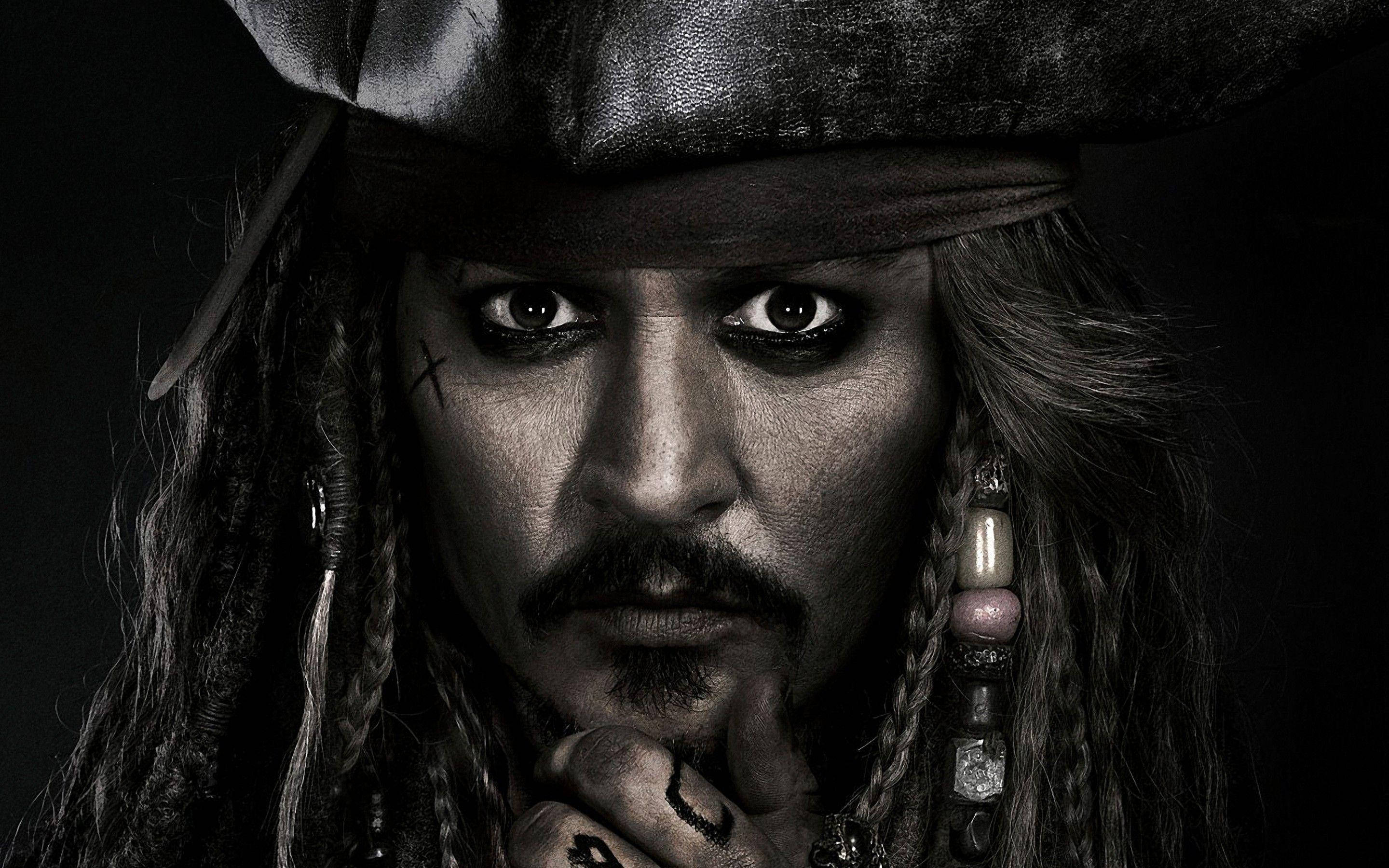 Pirates Of The Caribbean 桌布 壁紙 — 海盜的近距離肖像，眼神銳利，留著長髮辮，戴著黑色帽子，背景陰暗。