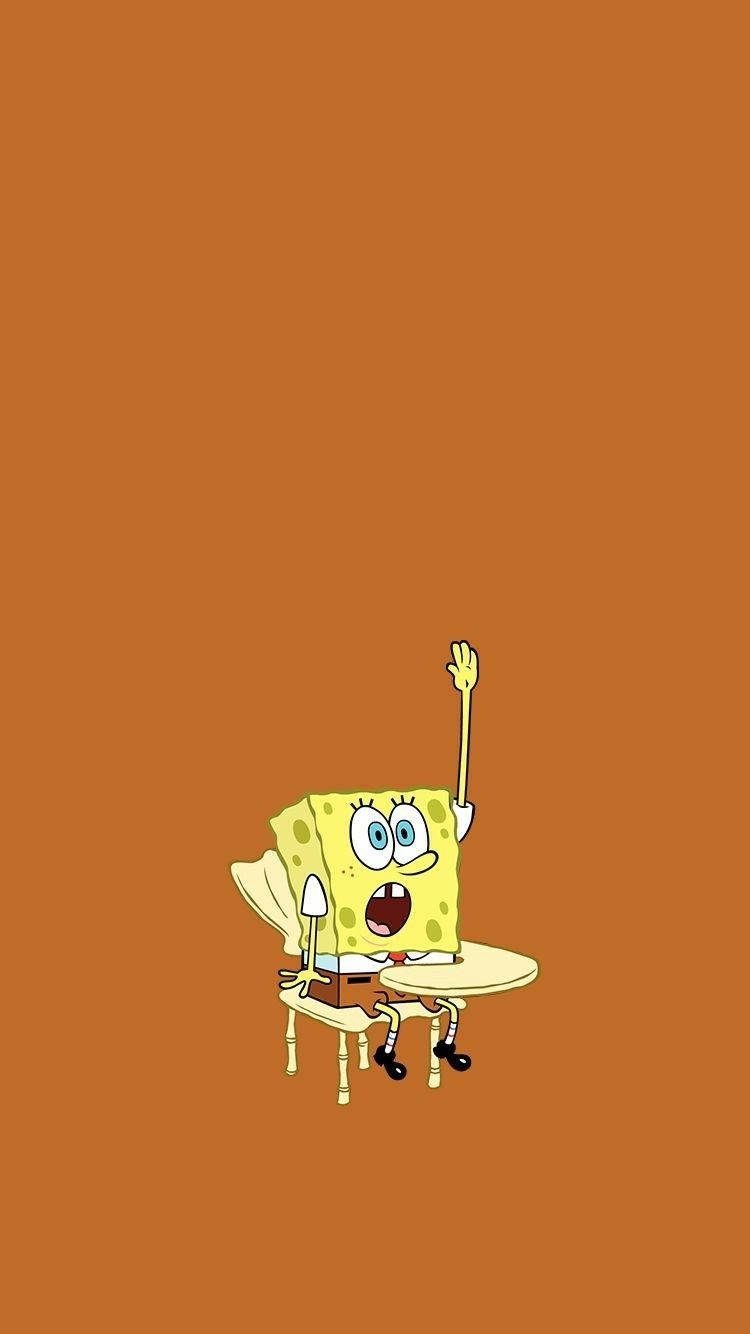 Funny Spongebob 桌布 壁紙 — 海綿寶寶坐在小桌子旁，在純橙色背景前熱情地揮手。