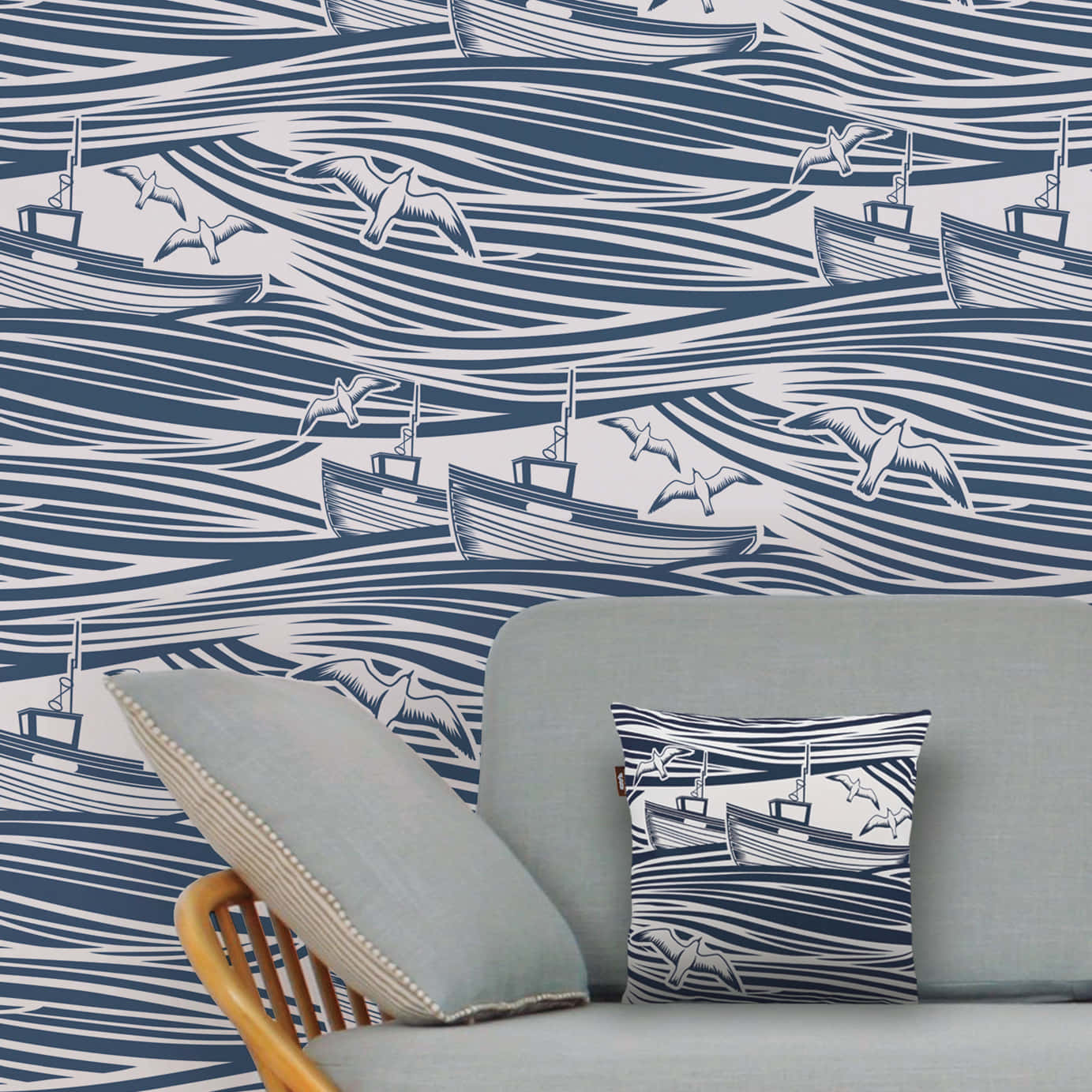 Nautical 桌布 壁紙 — 海軍藍和白色航海風格壁紙，帶有風格化的漁船和海鷗在波浪線上，搭配灰色沙發和相配的枕頭。