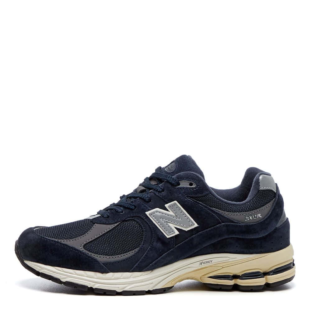 New Balance 桌布 壁紙 — 海軍藍色 New Balance 2002R 運動鞋，銀色標誌和米色鞋底，在工作室燈光下展示。