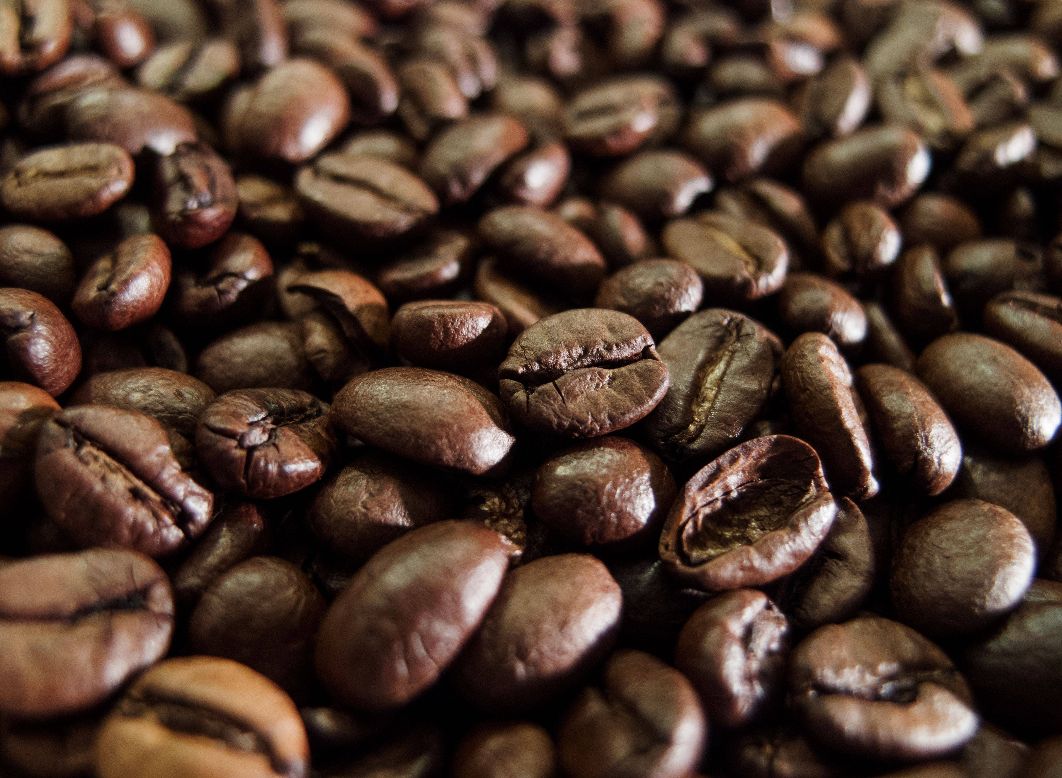 beans 桌布 壁紙 — 深棕色烘焙咖啡豆的特寫，表面帶有紋理和自然裂紋。