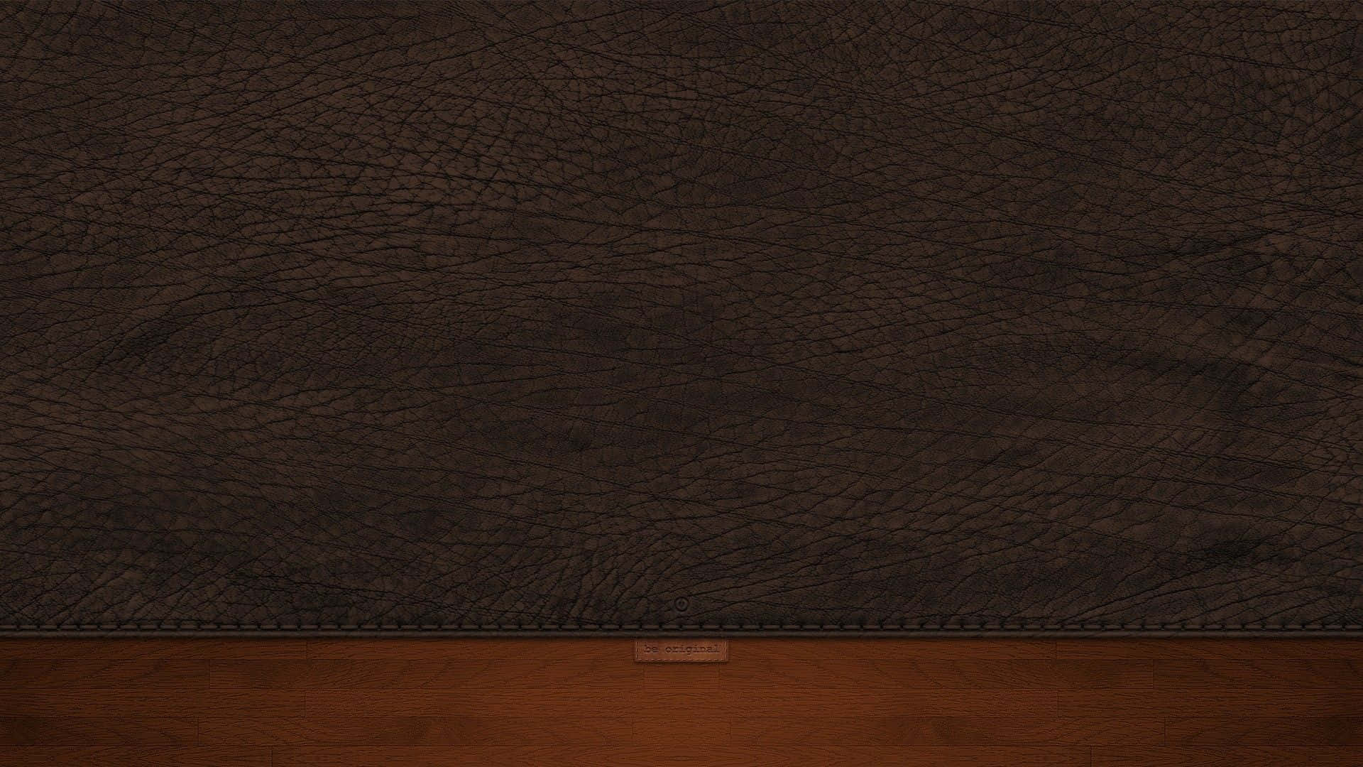 Leather 桌布 壁紙 — 深棕色皮革帶有自然皺褶，在縫合接縫處與木質表面相接的特寫。