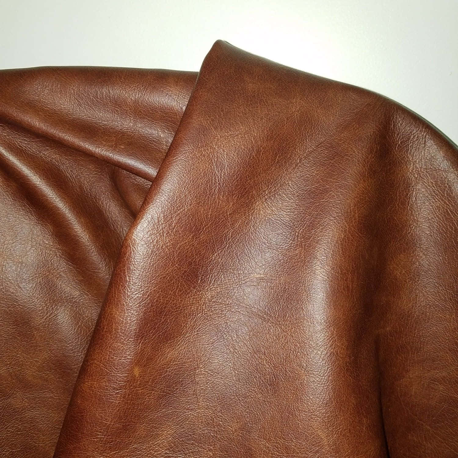 texture 桌布 壁紙 — 深棕色皮革的特寫，帶有自然皺紋和微妙光澤，背景為純白色。