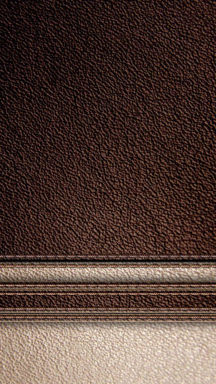 Leather 桌布 壁紙 — 深棕色紋理皮革的特寫，帶有對比鮮明的淺米色縫合接縫，將框架一分為二。