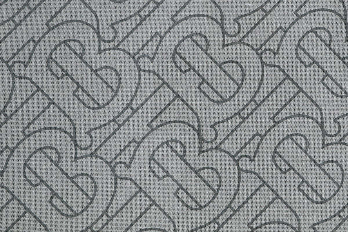 Burberry 桌布 壁紙 — 深灰色交織B字母重複字母組合圖案，背景為帶紋理的淺灰色布料。