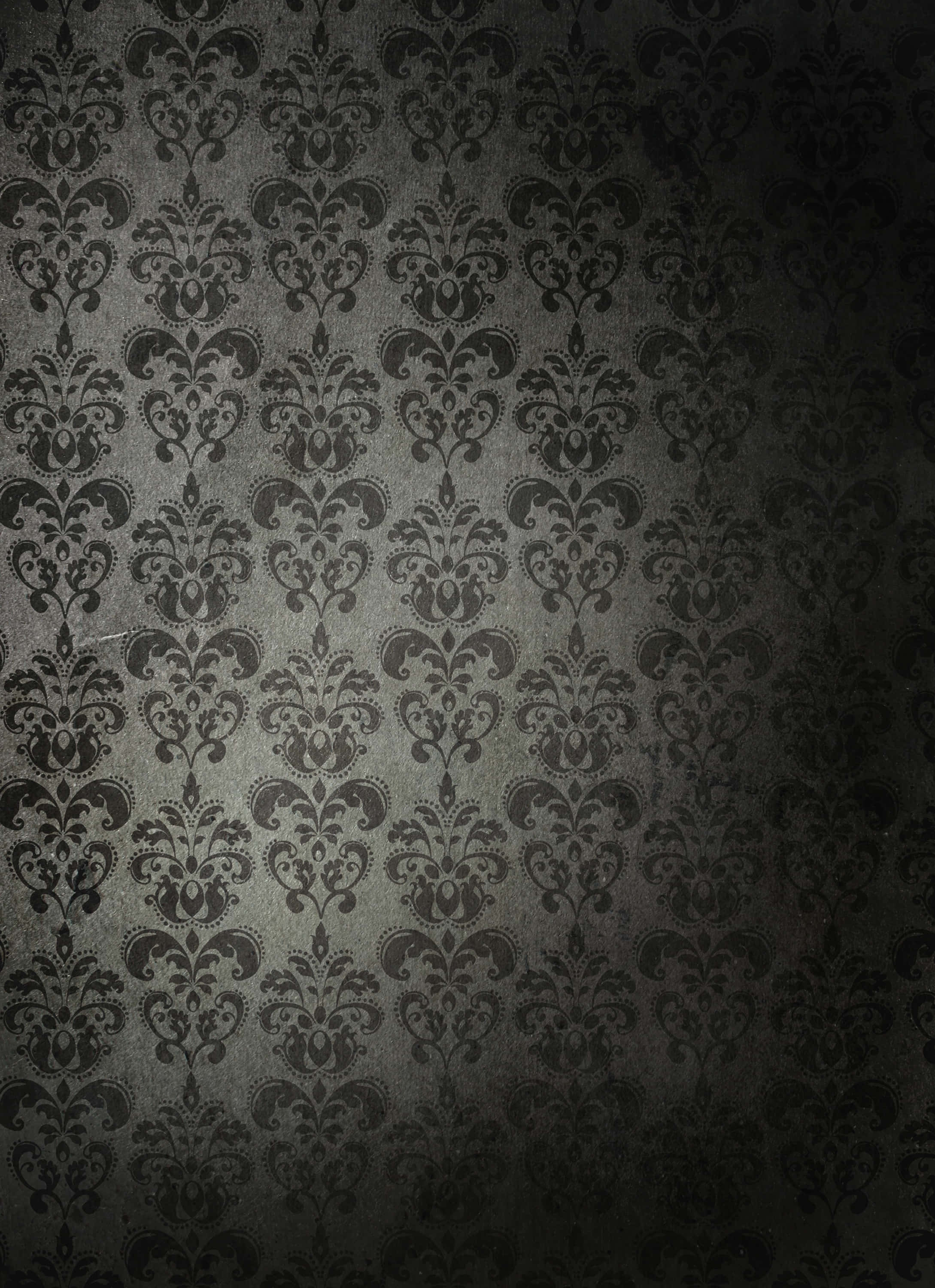 fancy 桌布 壁紙 — 深灰色大馬士革花紋壁紙，在昏暗燈光下呈現複雜花卉圖案和紋理表面。