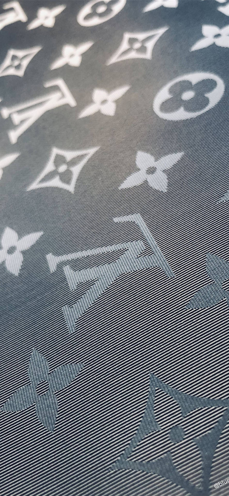 深灰色布料，帶有白色 Louis Vuitton 字母圖案和花卉圖案。