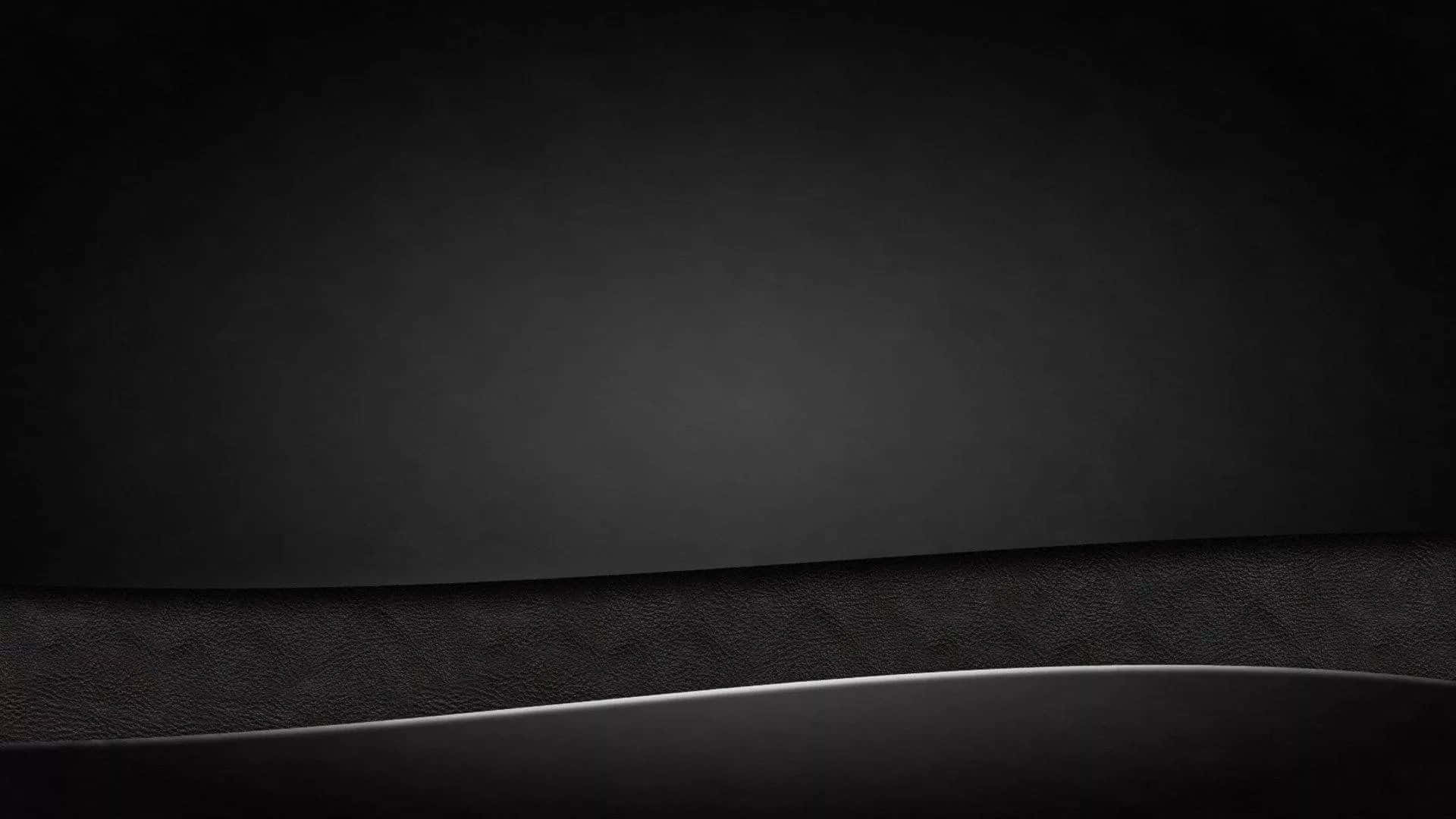 Plain Black Desktop 桌布 壁紙 — 深灰色皮革紋理的極簡漸變，帶有微妙的弧形高光。
