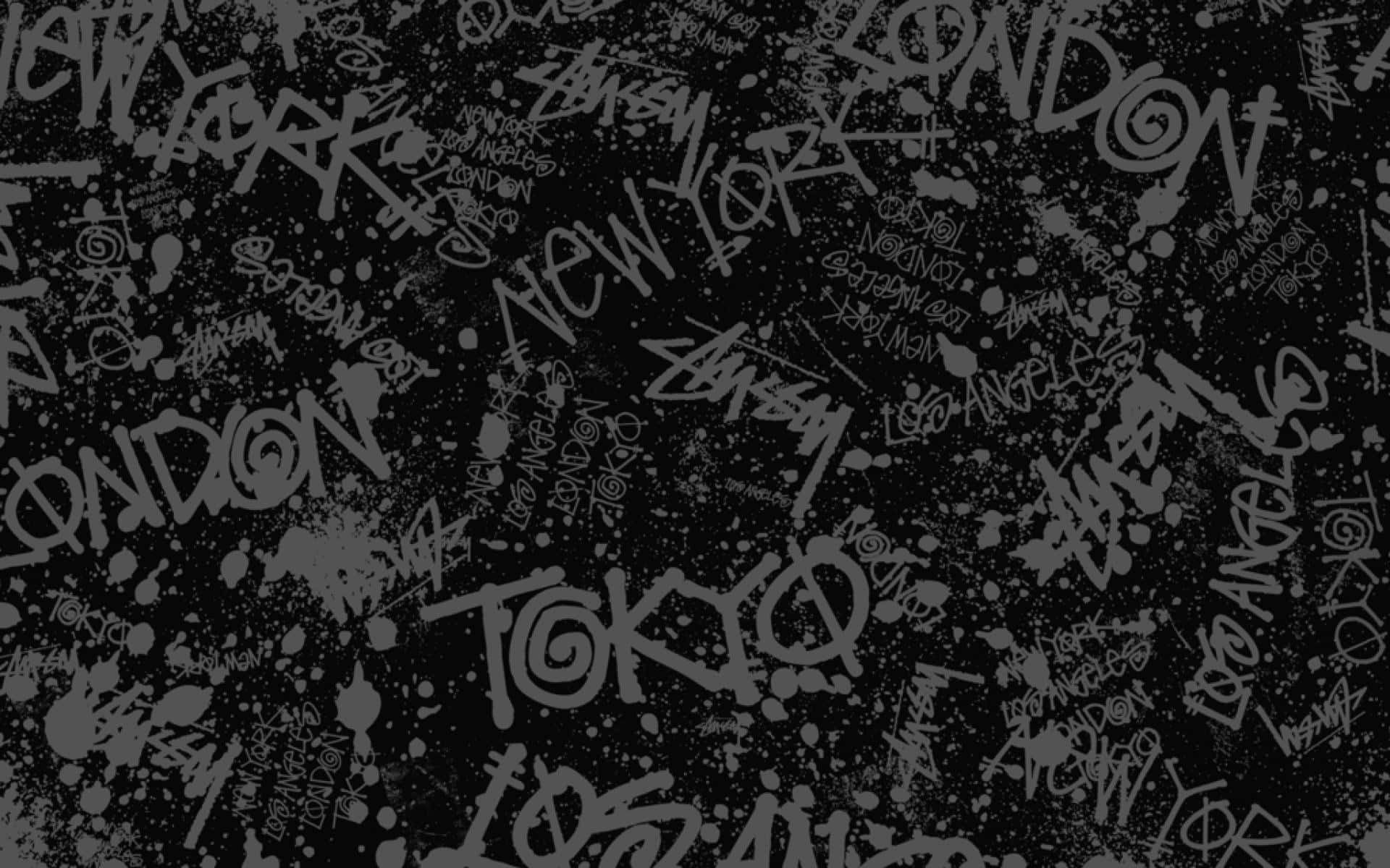 Grunge Aesthetic Mac 桌布 壁紙 — 深灰色紋理背景，上面覆蓋著重疊的塗鴉風格城市名稱，如東京和紐約，並帶有飛濺痕跡。