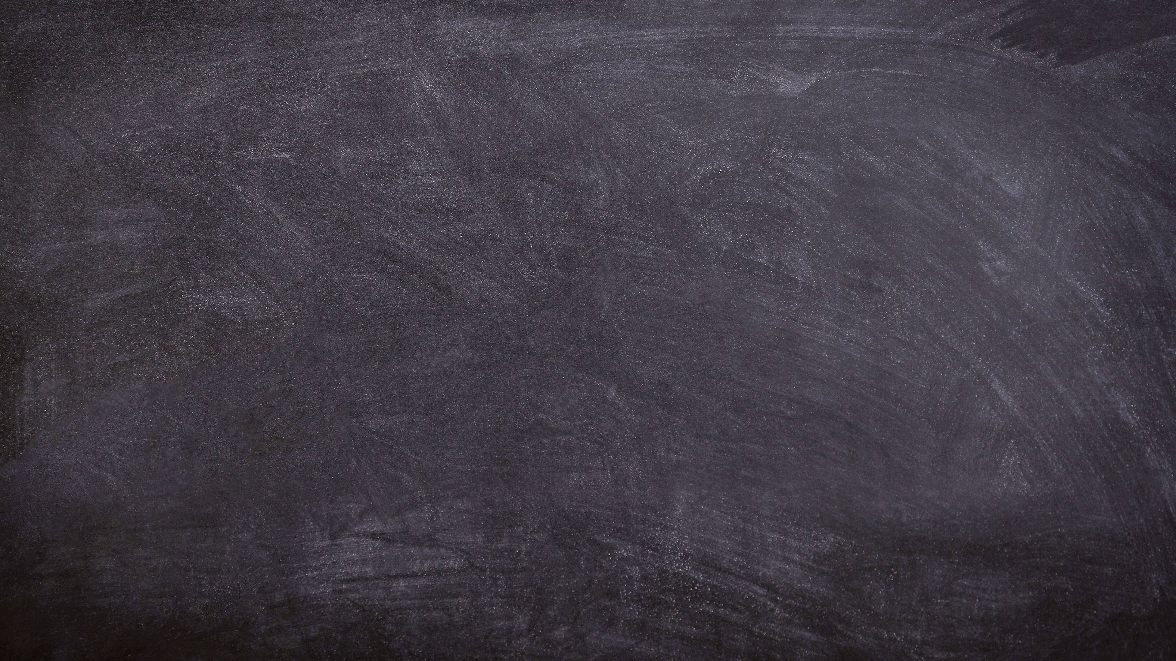 Chalkboard 桌布 壁紙 — 深灰色黑板表面的特寫，可見粉筆灰和模糊的書寫痕跡。