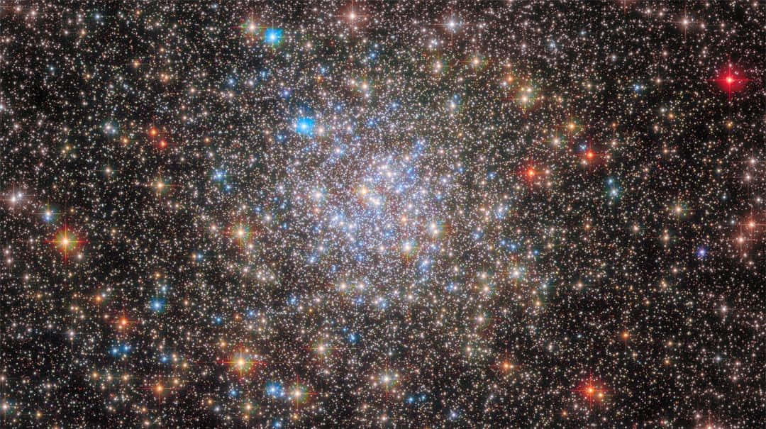 Galactic Center 桌布 壁紙 — 深空中密集的星團在黑色宇宙背景下散發出鮮豔的藍色、紅色和黃色。