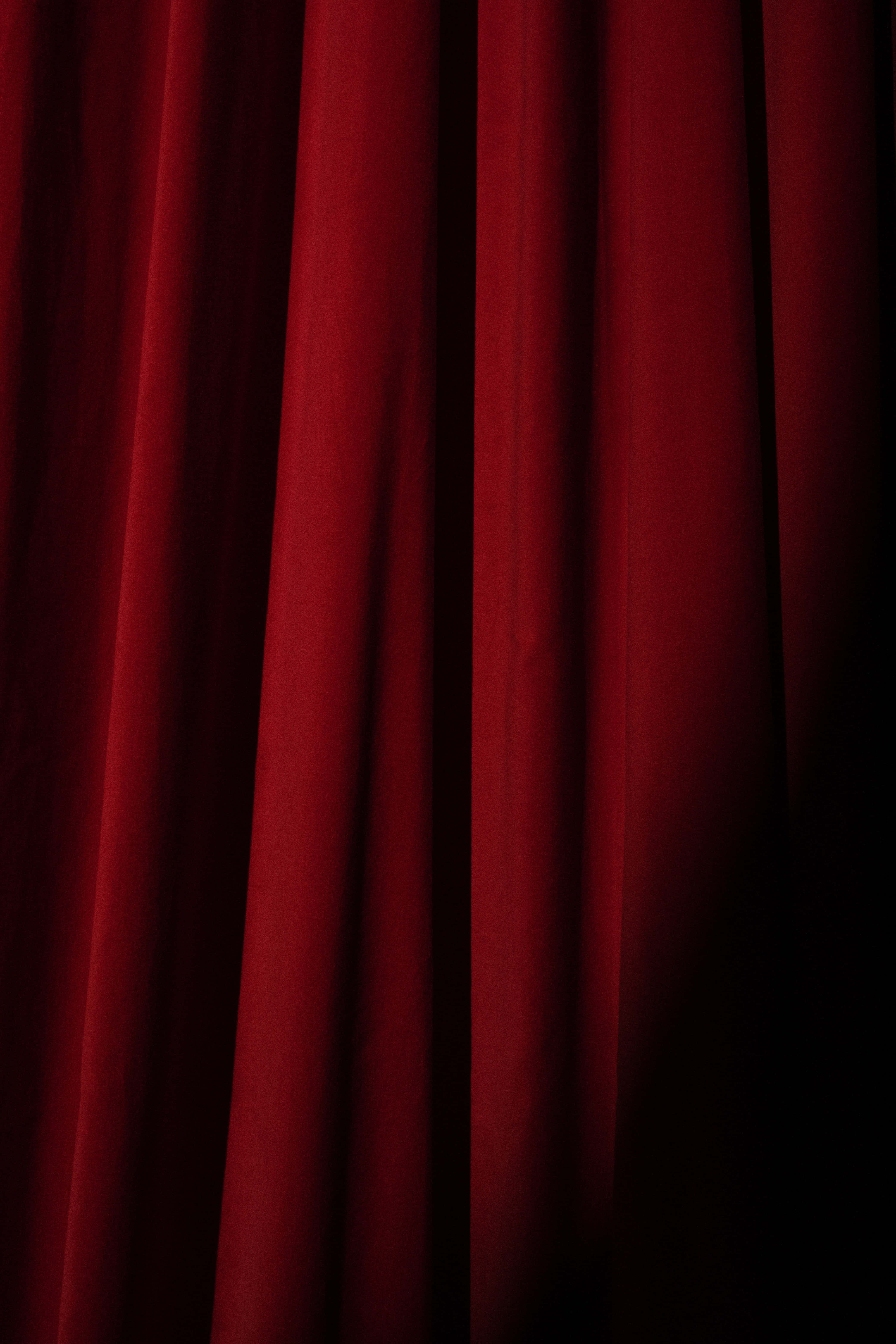 Red Curtain 桌布 壁紙 — 深紅色天鵝絨窗簾褶皺，由戲劇性的側光照射，投射出豐富的陰影。