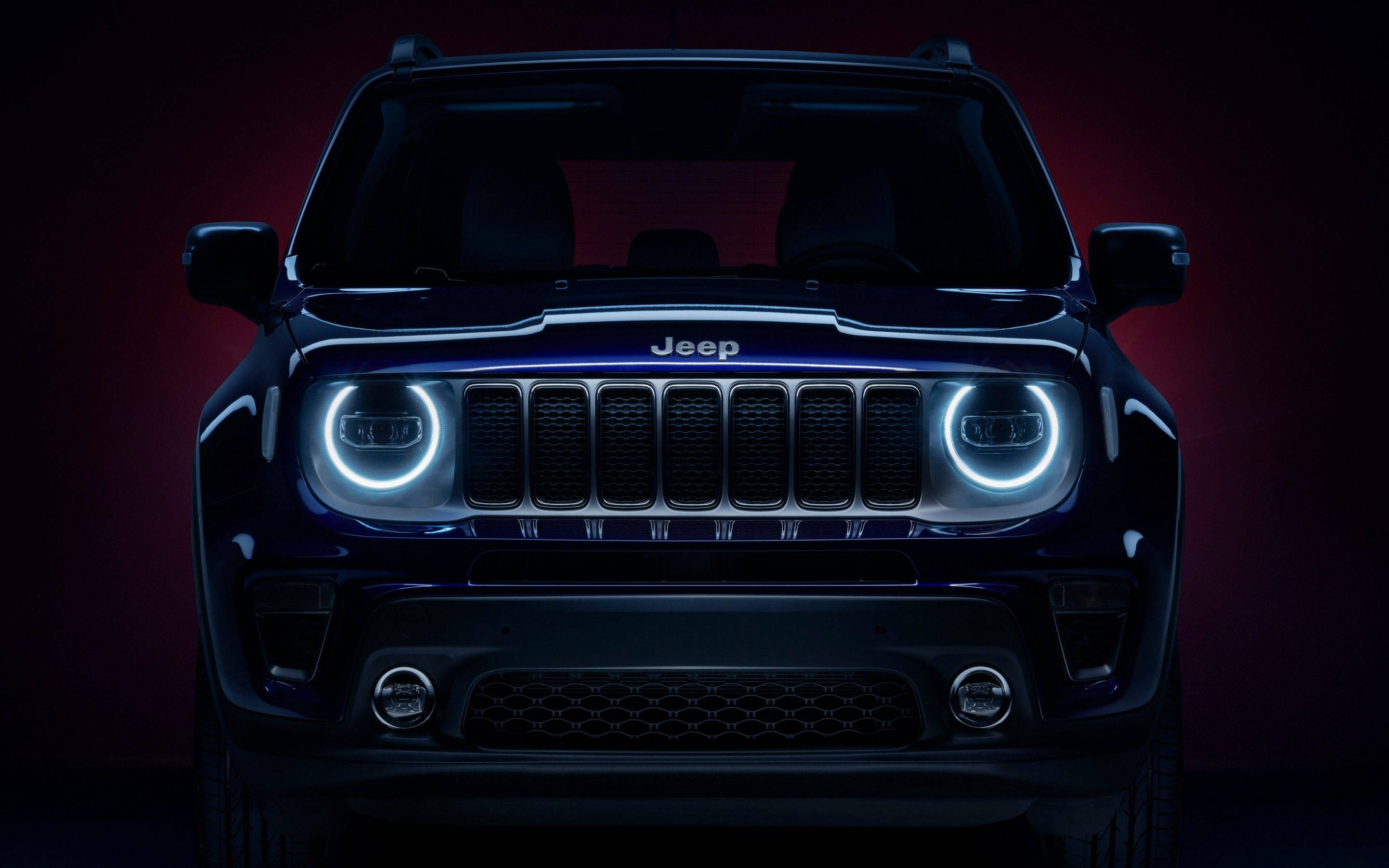 Wrangler 桌布 壁紙 — 深紅色背景前，一輛深藍色Jeep SUV的前視圖，帶有發光的環形頭燈。