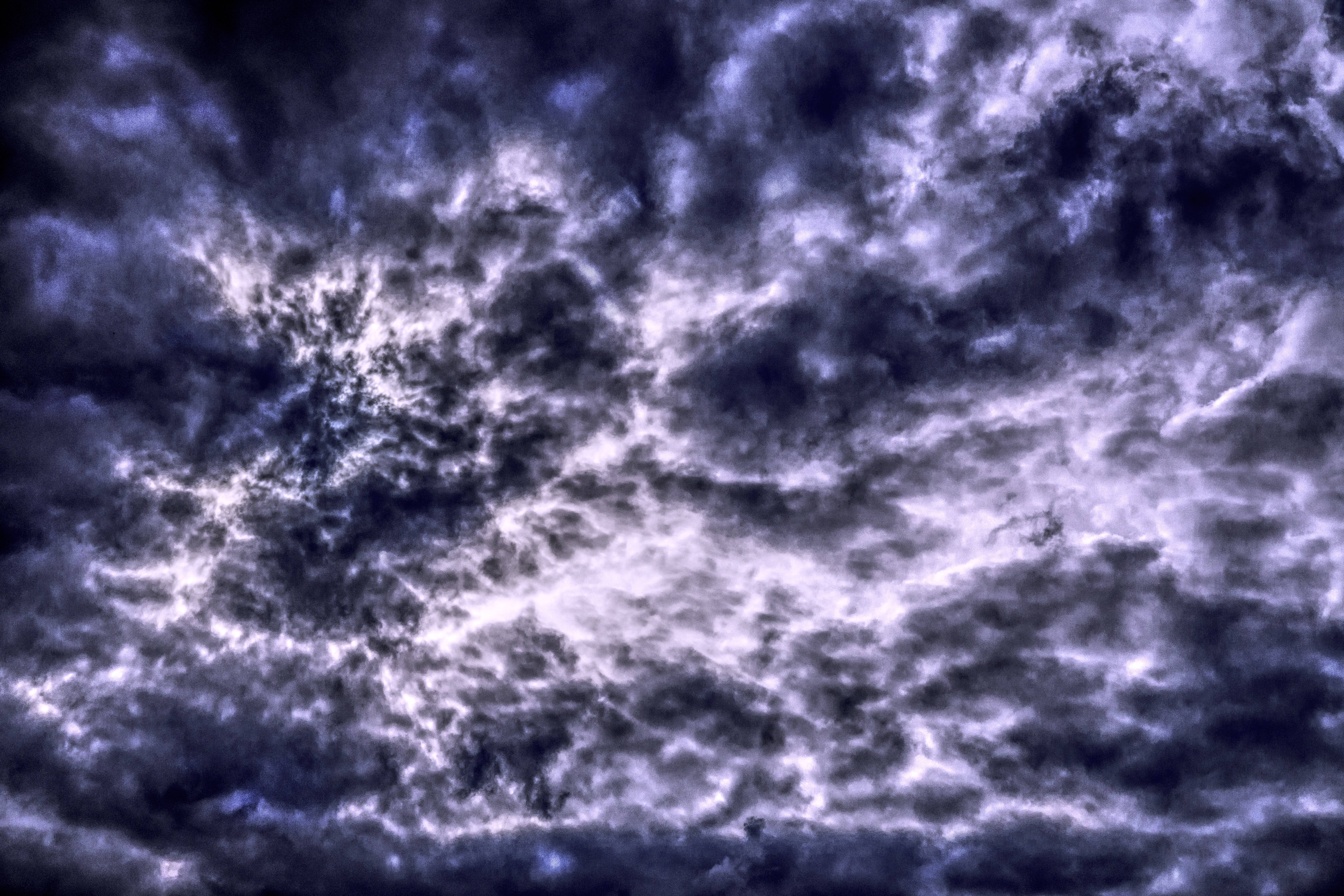 雲朵 桌布 壁紙 — 深紫色和白色的戲劇性漩渦雲層充滿天空，營造出不祥而動盪的氛圍。