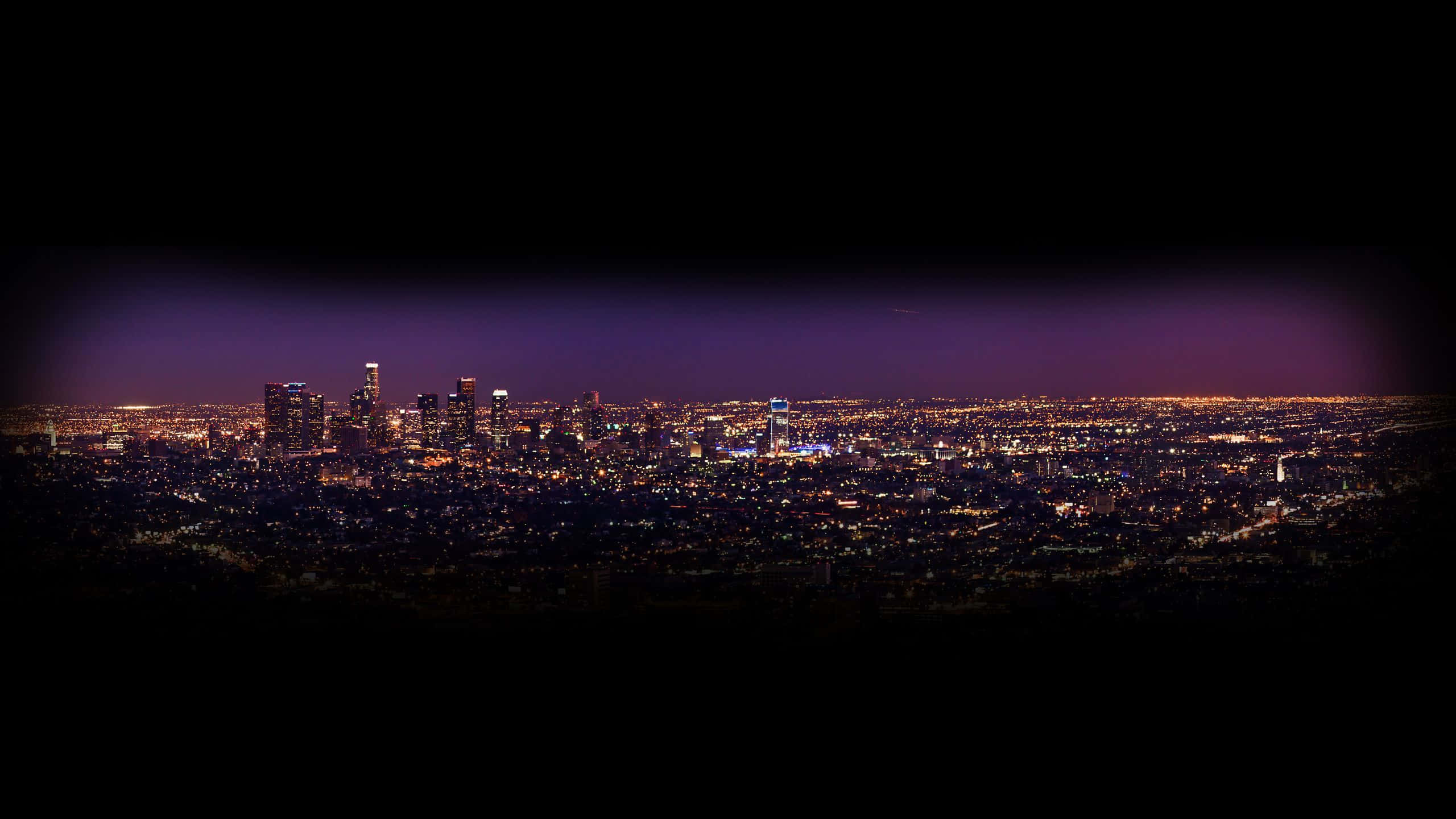 Aesthetic YouTube Banner 桌布 壁紙 — 深紫色天空下，廣闊城市景觀閃爍著無數燈光的全景夜景。