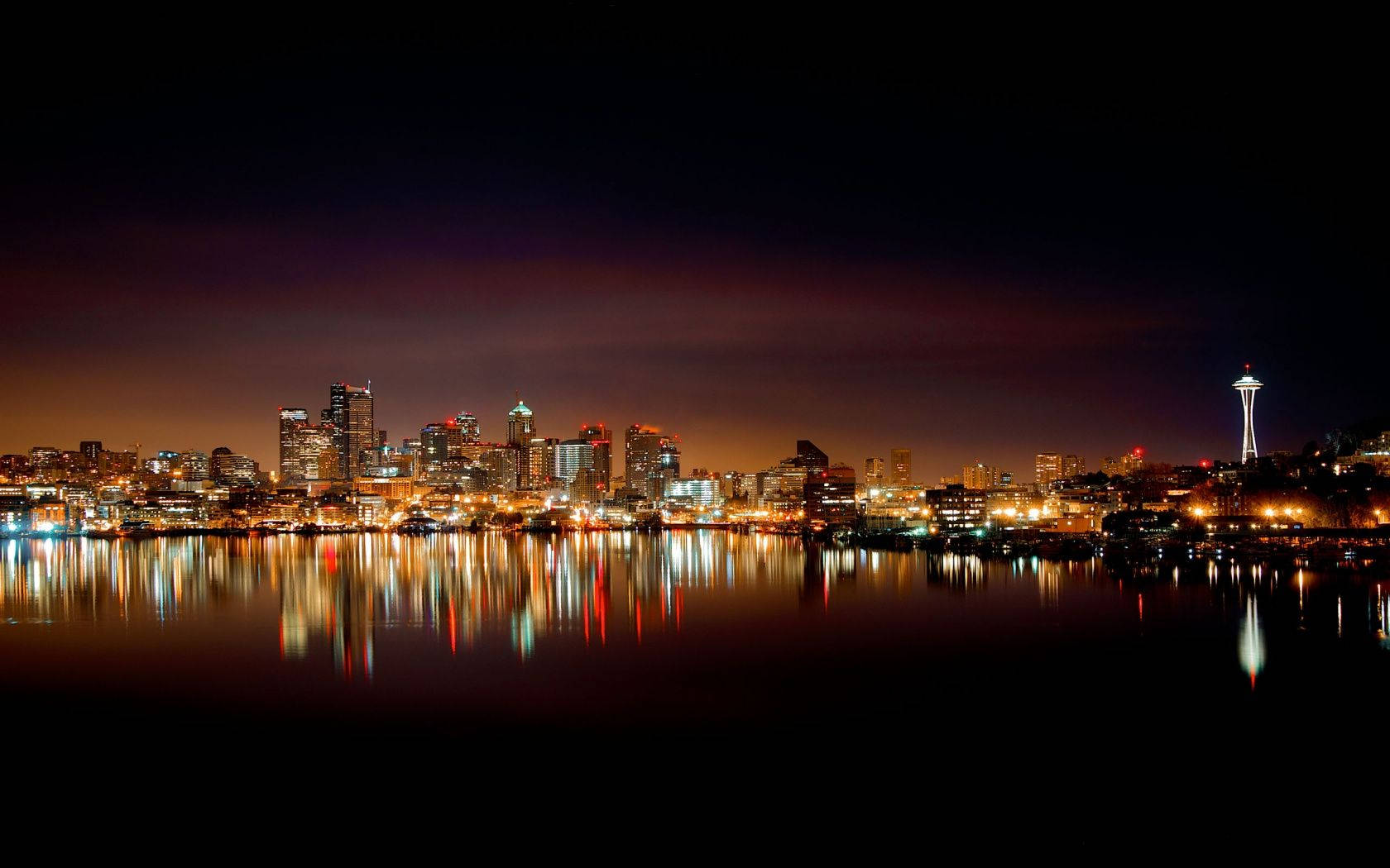 Seattle Skyline 桌布 壁紙 — 深紫色天空下，西雅圖天際線夜景，太空針塔亮燈並倒映在暗水中。