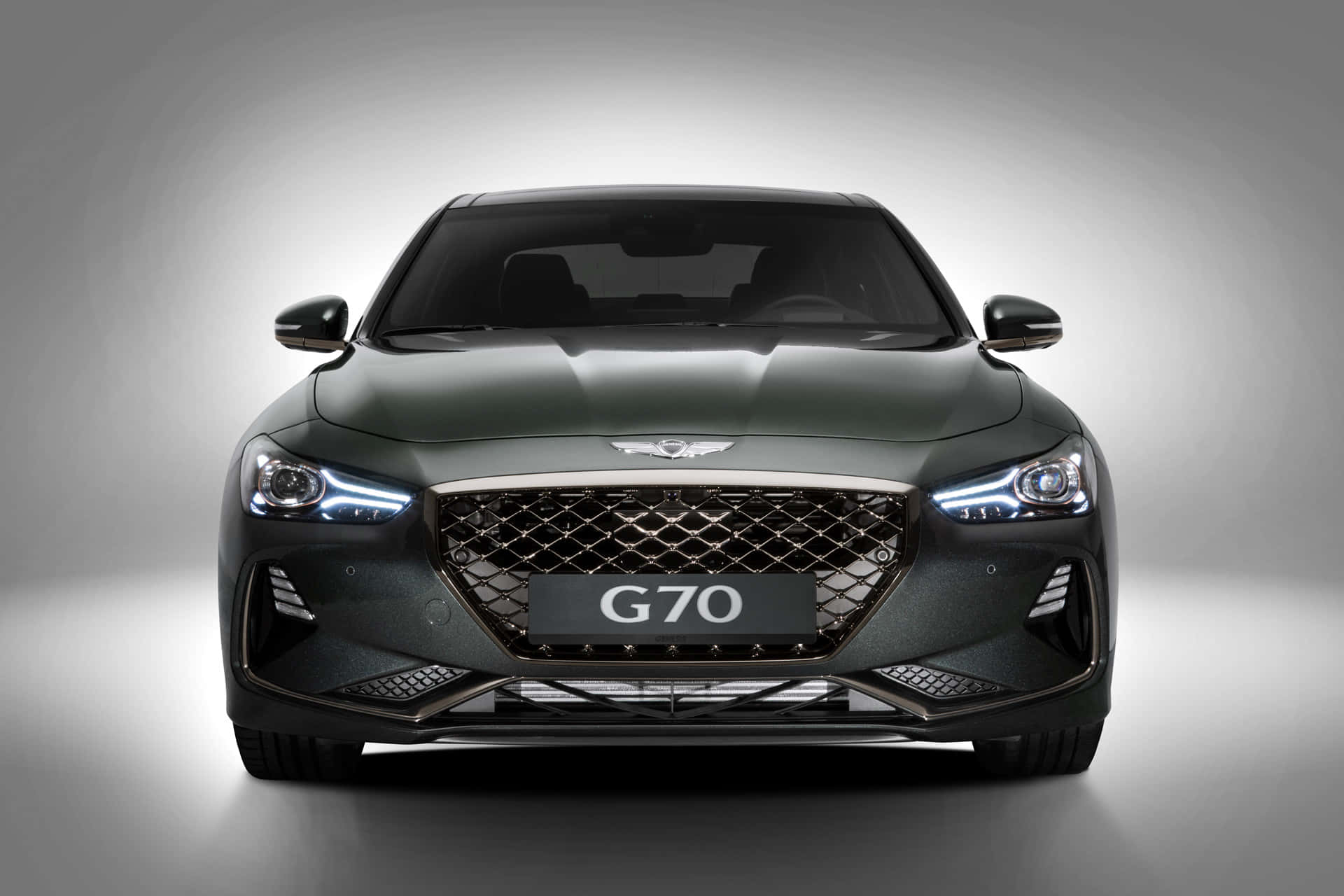 創世紀 桌布 壁紙 — 深綠色 Genesis G70 運動轎車的正面視圖，帶有發光頭燈，背景為漸變灰色工作室背景。