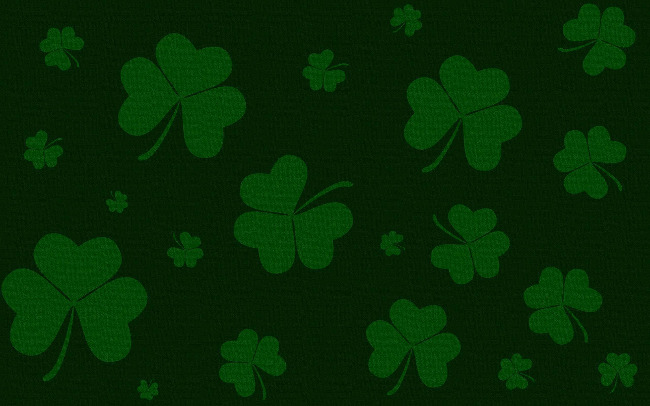 Saint Patricks Day 桌布 壁紙 — 深綠色背景上散佈著不同大小的淺綠色四葉草剪影。