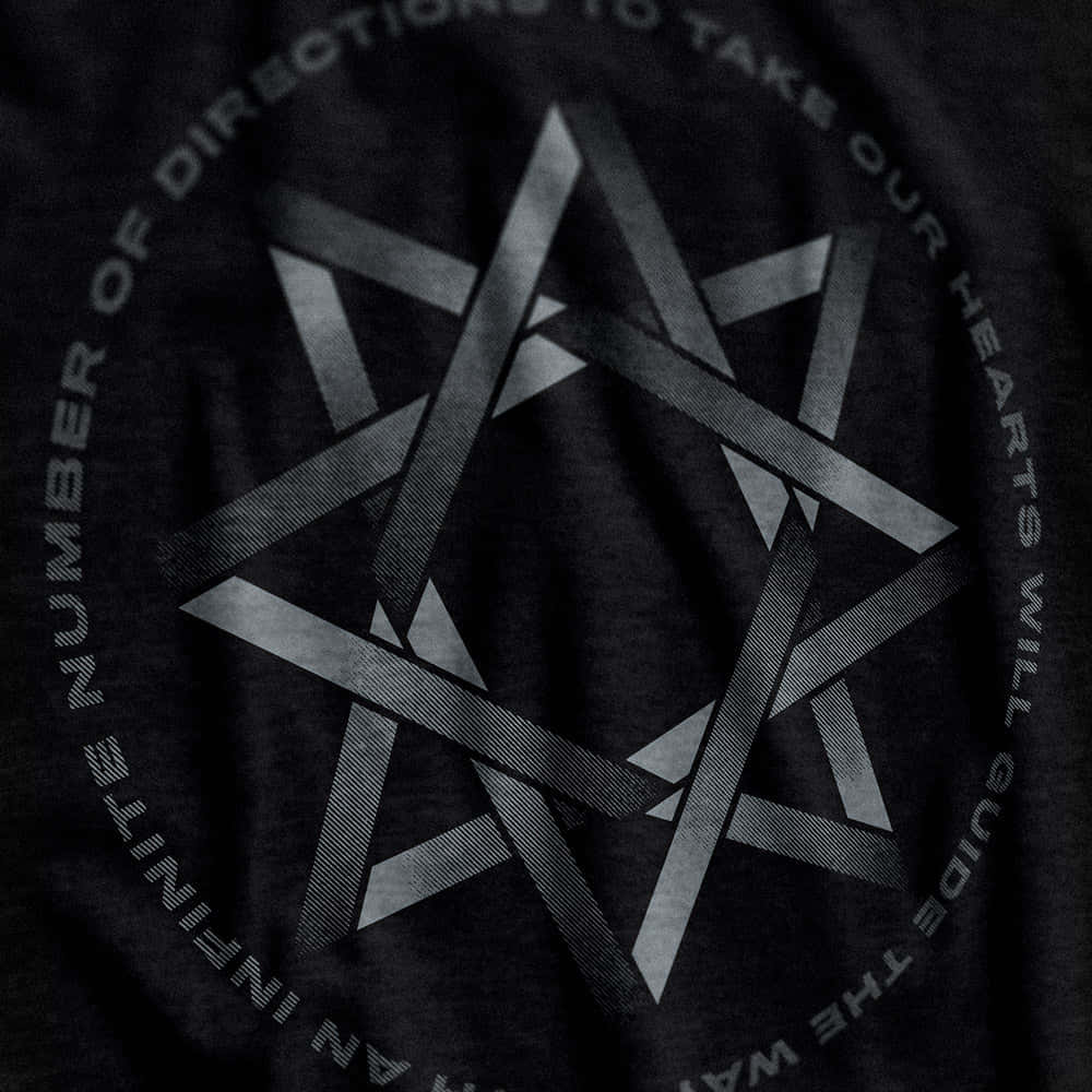 Thelema 桌布 壁紙 — 深色T恤的近距离特写，带有几何星形设计和银灰色环绕文字。