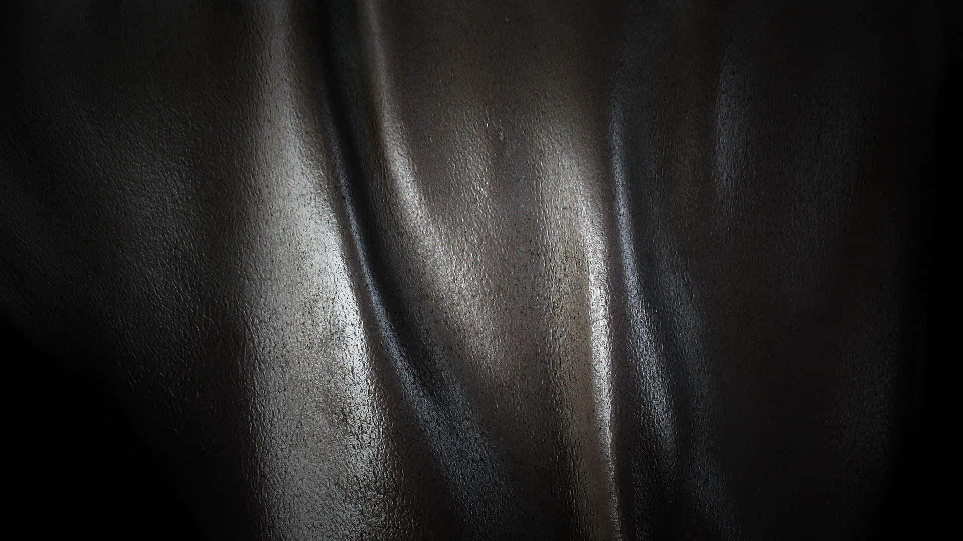 Leather 桌布 壁紙 — 深色光面皮革的特寫，帶有柔軟的摺痕和微妙的亮點，背景為黑色。