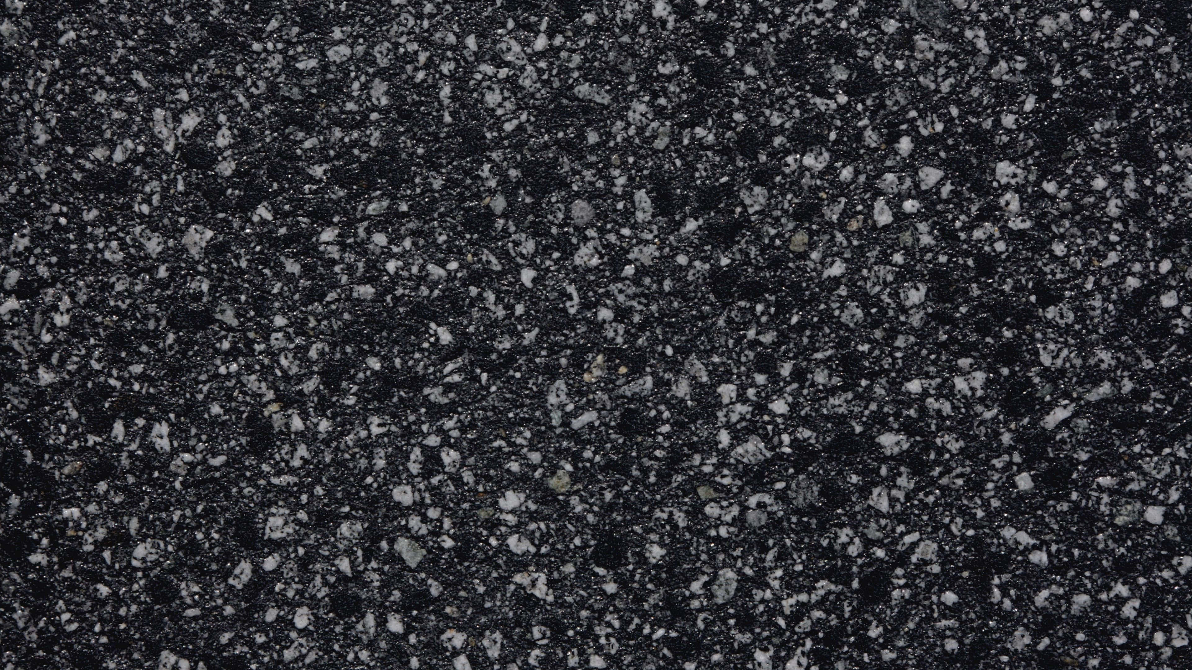 4K Marble 桌布 壁紙 — 深色斑點花崗岩表面的特寫，散佈著白色和灰色的礦物顆粒。
