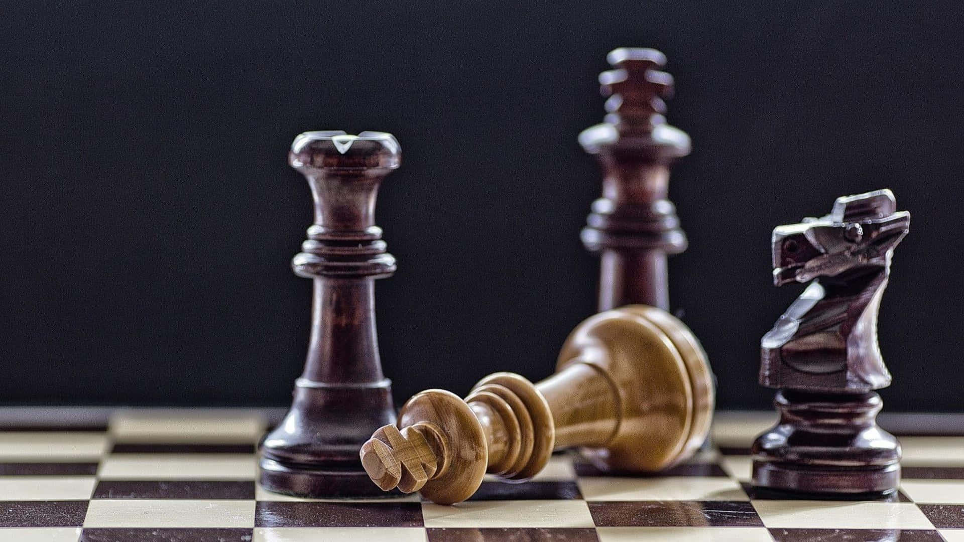 西洋棋 桌布 壁紙 — 深色木製西洋棋棋子在黑白格棋盤上站立和倒下，背景為黑色。