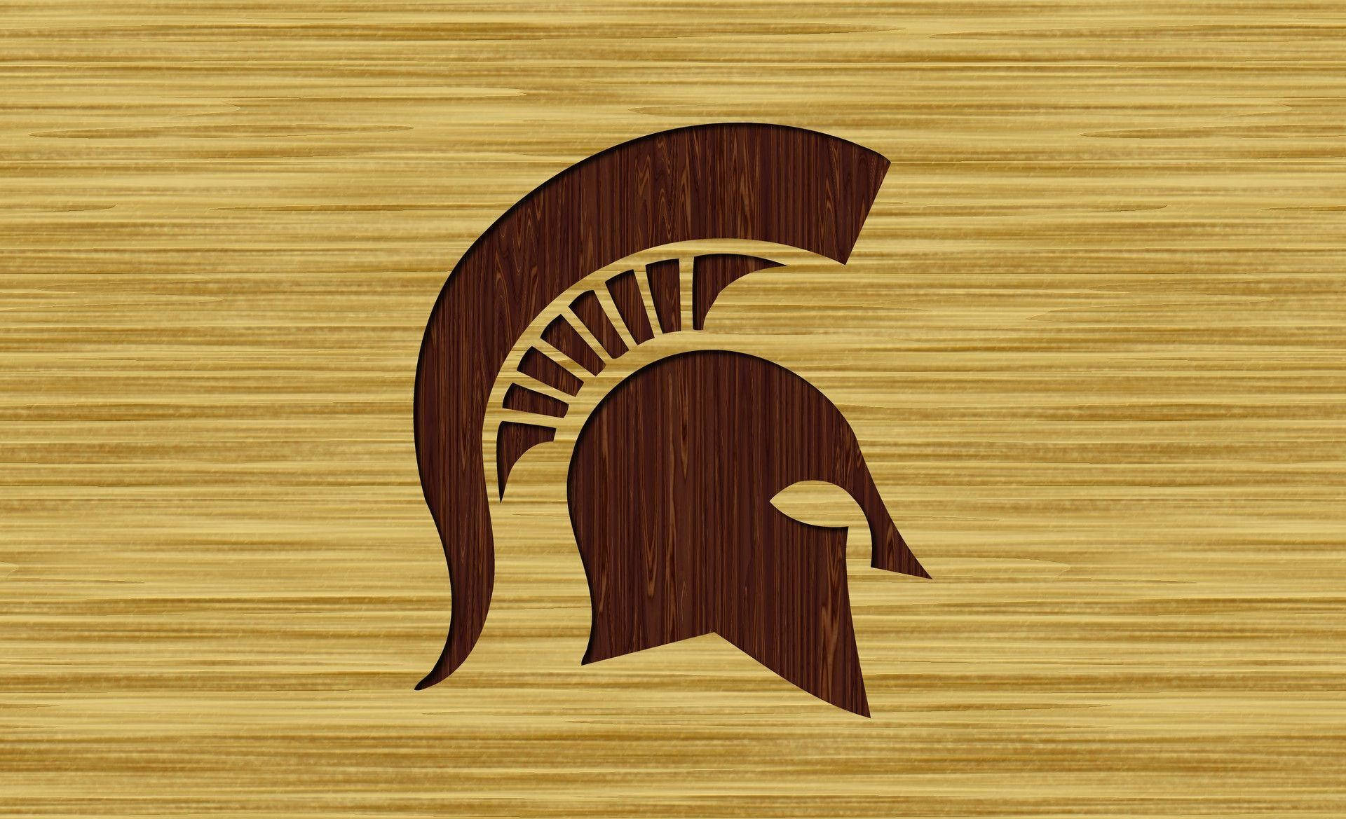 Michigan State Spartans 桌布 壁紙 — 深色木質斯巴達頭盔標誌在淺色木紋背景上脫穎而出。