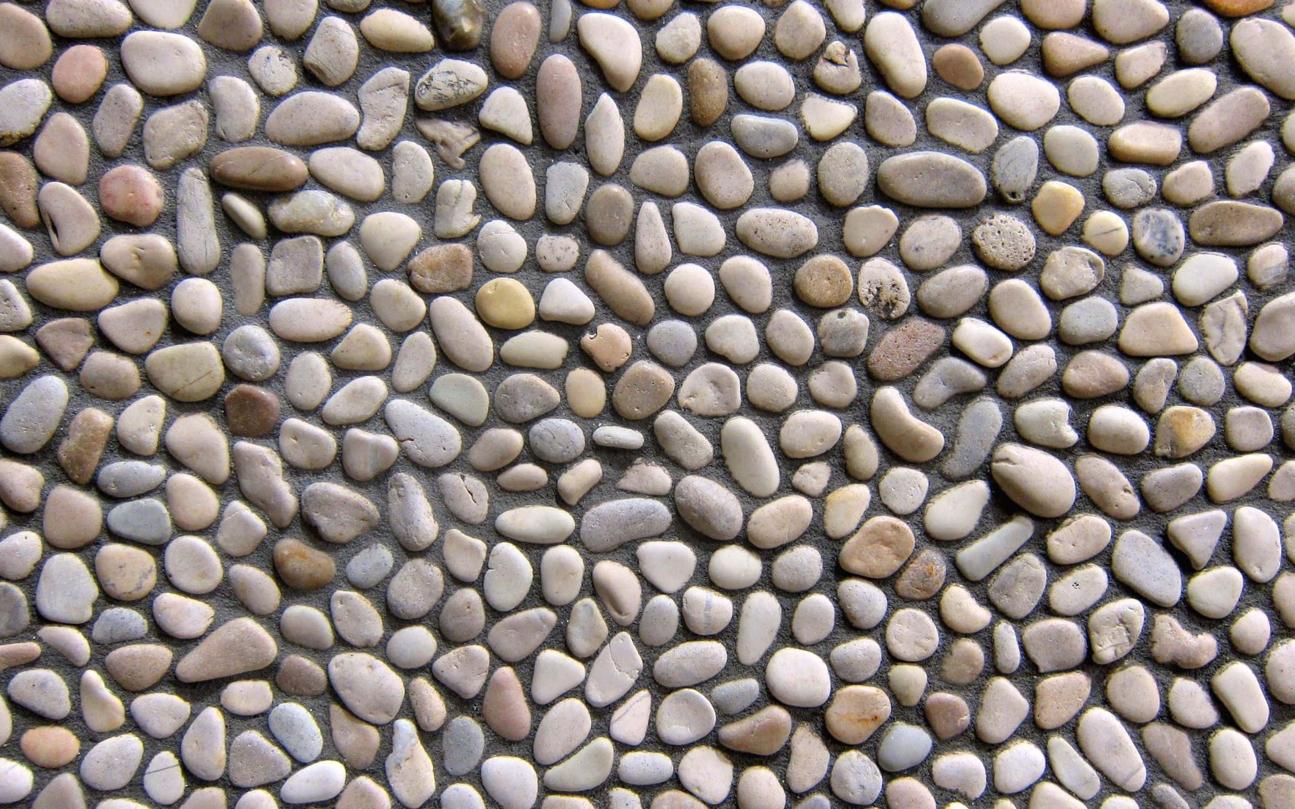 Stone 桌布 壁紙 — 深色沙中嵌入中性色調光滑圓形卵石的近距離特寫，形成紋理自然馬賽克。