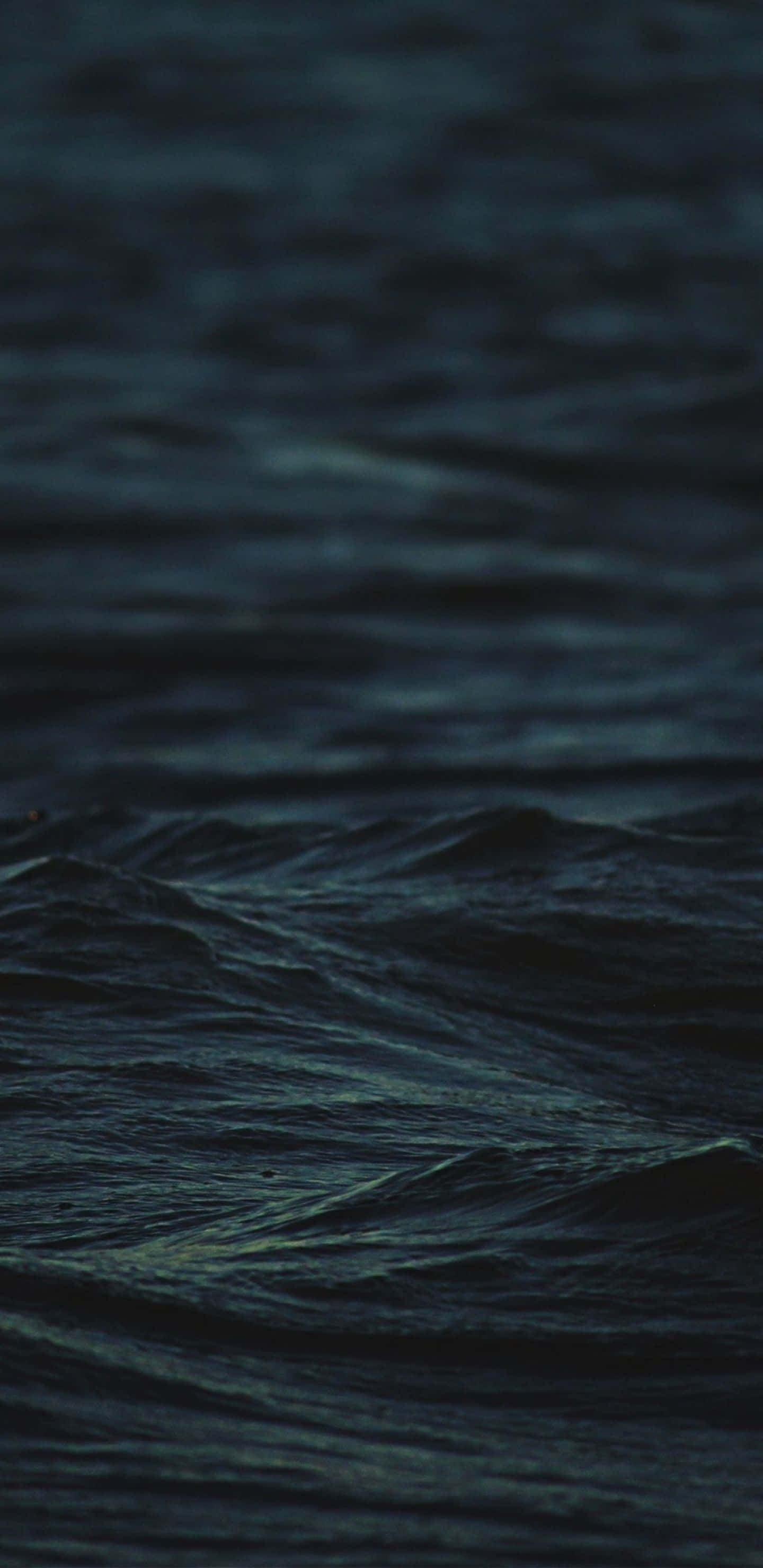 Dark Ocean 桌布 壁紙 — 深色海浪在昏暗光線下蕩漾，深藍色和藍綠色調營造出憂鬱的夜間海景。