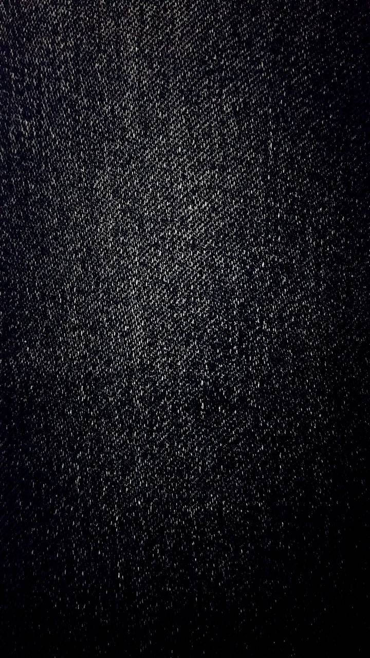 丹寧 桌布 壁紙 — 深色牛仔布料的特寫，帶有細微的白色斑點和斜紋編織質感，在柔和光線下呈現。