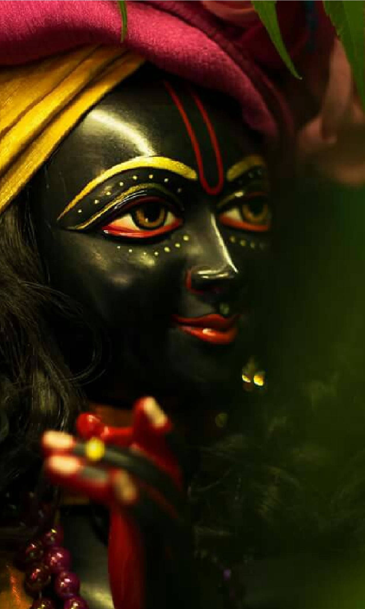 hindu iPhone 桌布 壁紙 — 深色皮膚神像特寫，帶有鮮豔的紅色、黃色和金色面部標記及彩色頭巾。