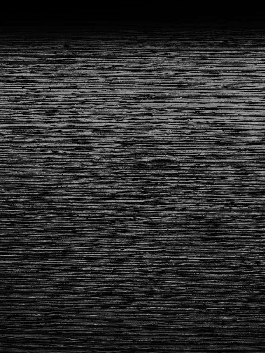 Black Wood 桌布 壁紙 — 深色紋理紙張的特寫，帶有細微的水平摺痕和微妙的灰色高光，背景為黑色漸變。