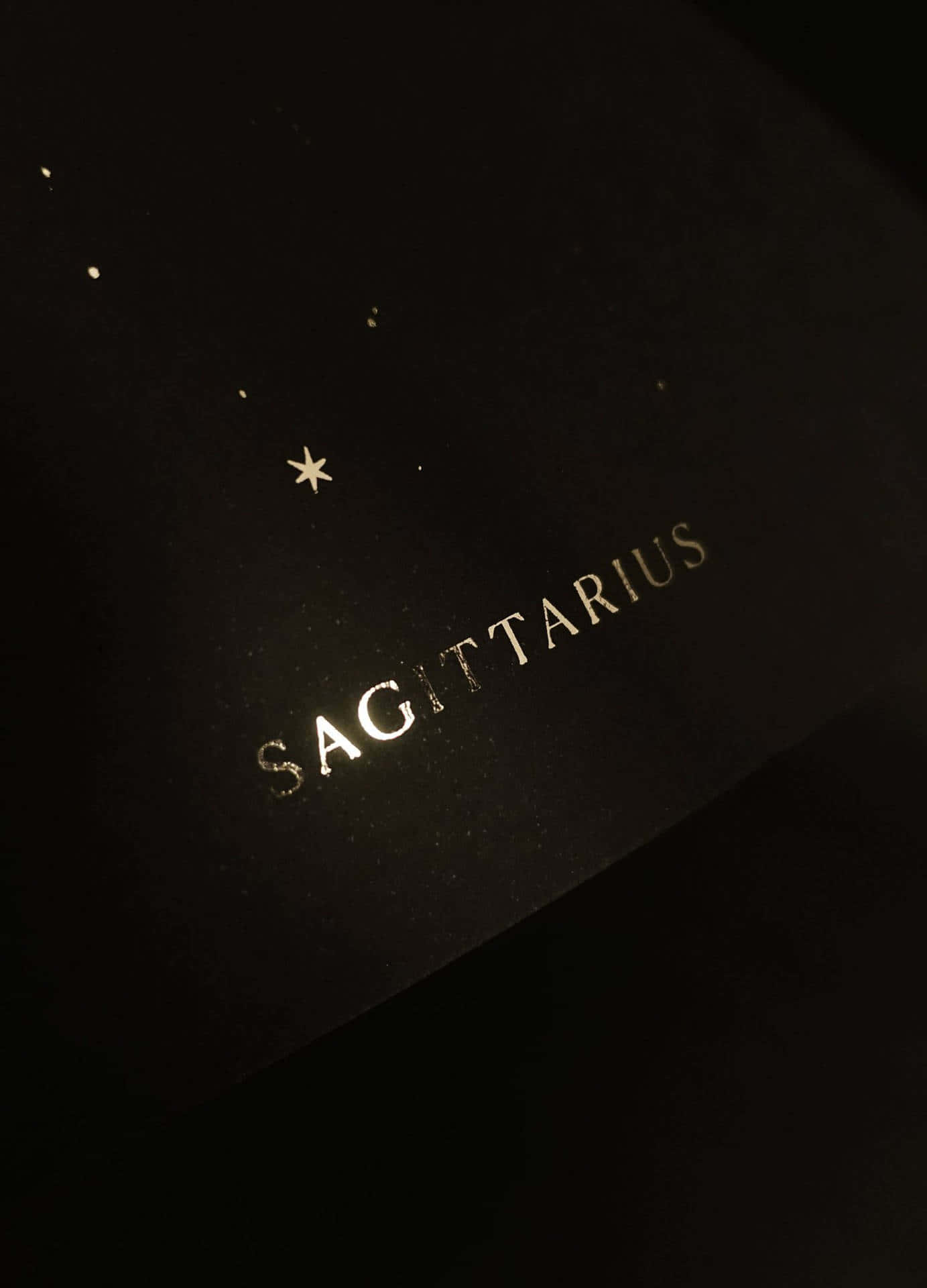 sagittarius 桌布 壁紙 — 深色紋理表面上，以金箔呈現「Sagittarius」字樣，上方散落著金色星星。