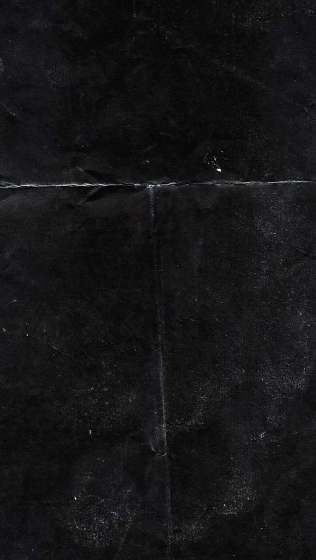 Black Plastic 桌布 壁紙 — 深色紋理黑紙的特寫，帶有可見的摺痕和微妙的表面瑕疵。