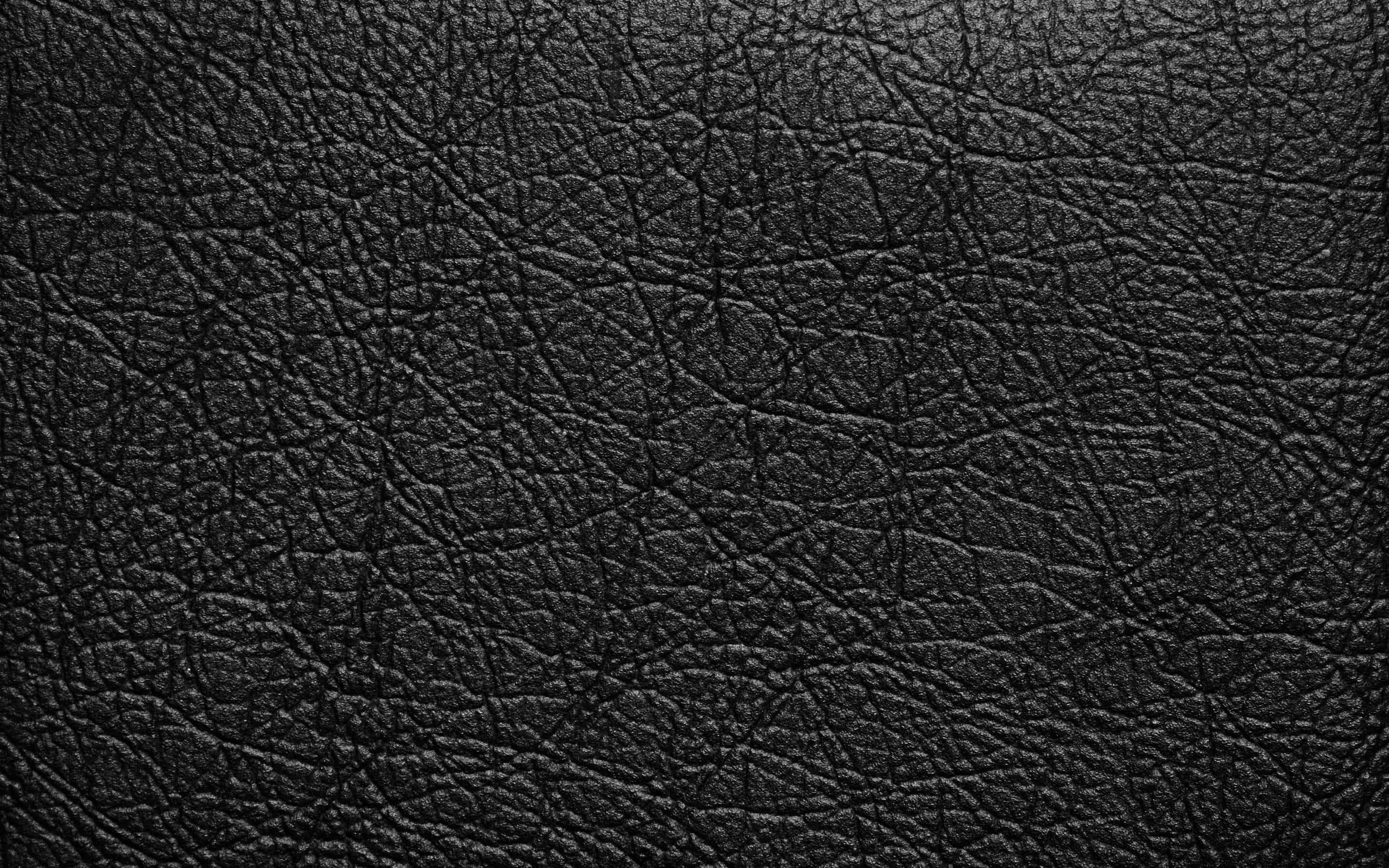 Black Leather 桌布 壁紙 — 深色紋理黑色皮革表面的特寫，帶有細微的紋理圖案和柔和的光線高光。
