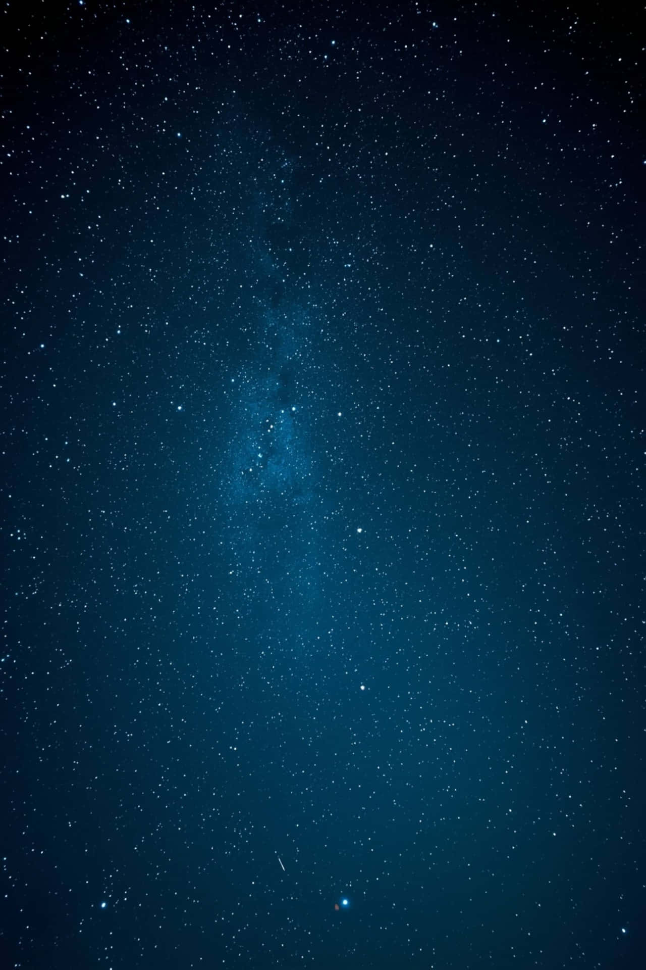 Starry night sky with deep blue tones and galaxy atmosphere 壁紙 — 深藍色夜空，充滿無數星星和銀河系的發光帶垂直延伸。