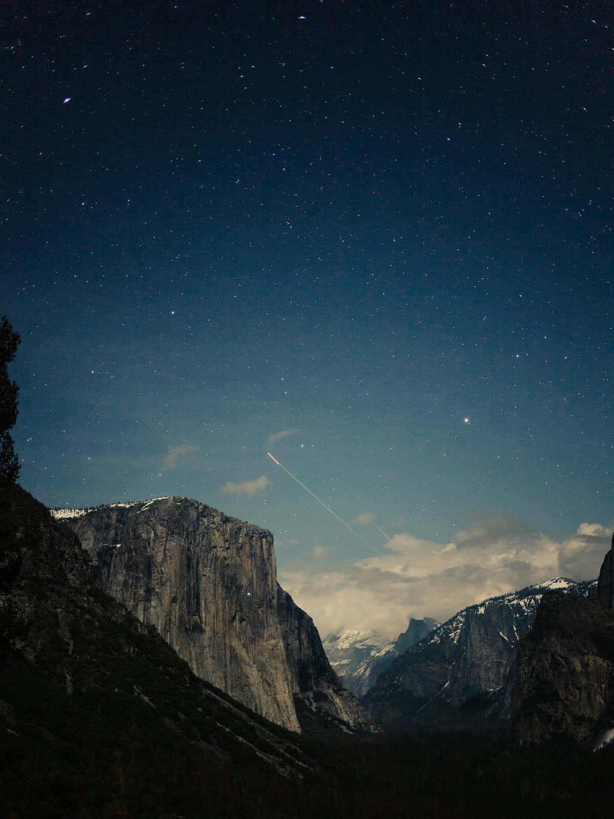 人像動態 桌布 壁紙 — 深藍色天空下，一顆明亮的流星劃過積雪覆蓋的山峰之上的星空夜空。