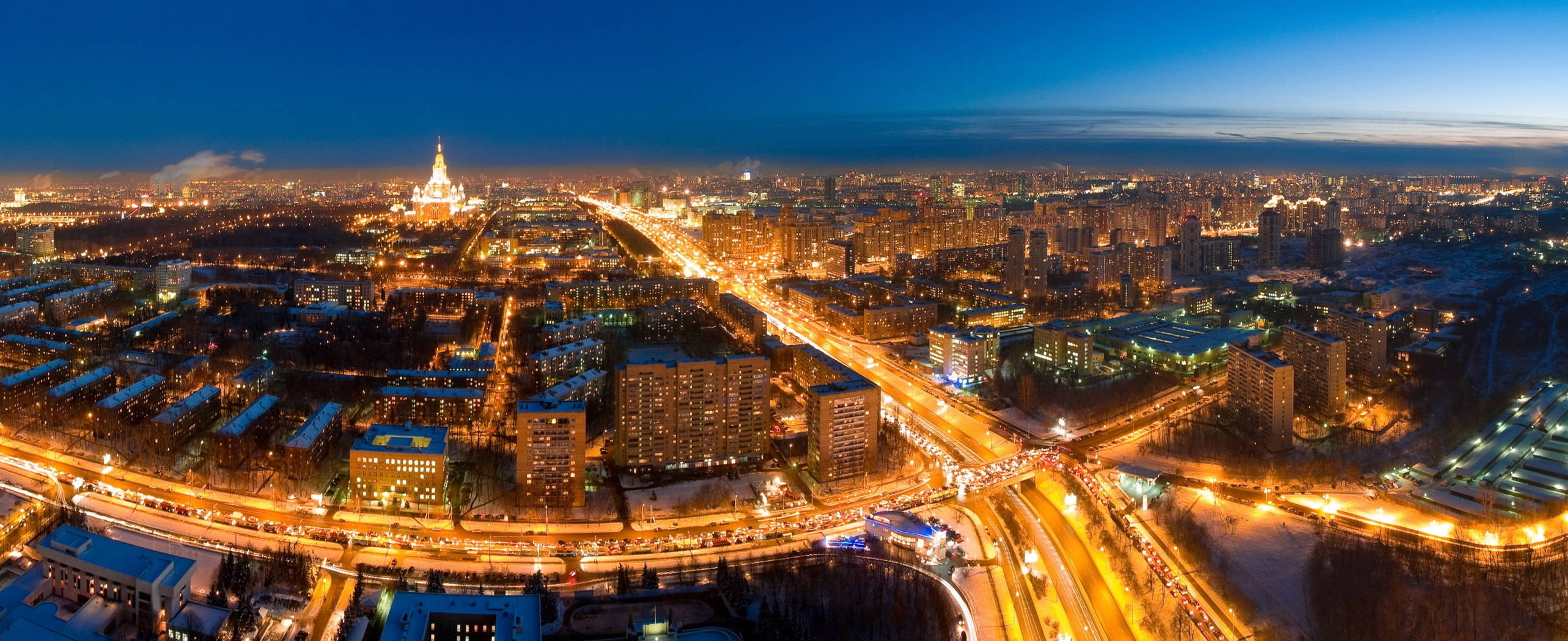 Moscow 桌布 壁紙 — 深藍色天空下，夜晚廣闊城市的鳥瞰圖，街道閃爍，屋頂覆蓋著白雪。