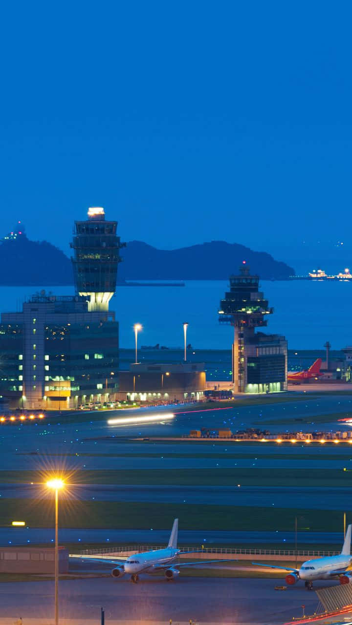 Airport 桌布 壁紙 — 深藍色天空下，暮色中機場的鳥瞰圖，發光的控制塔和停機坪上的飛機。