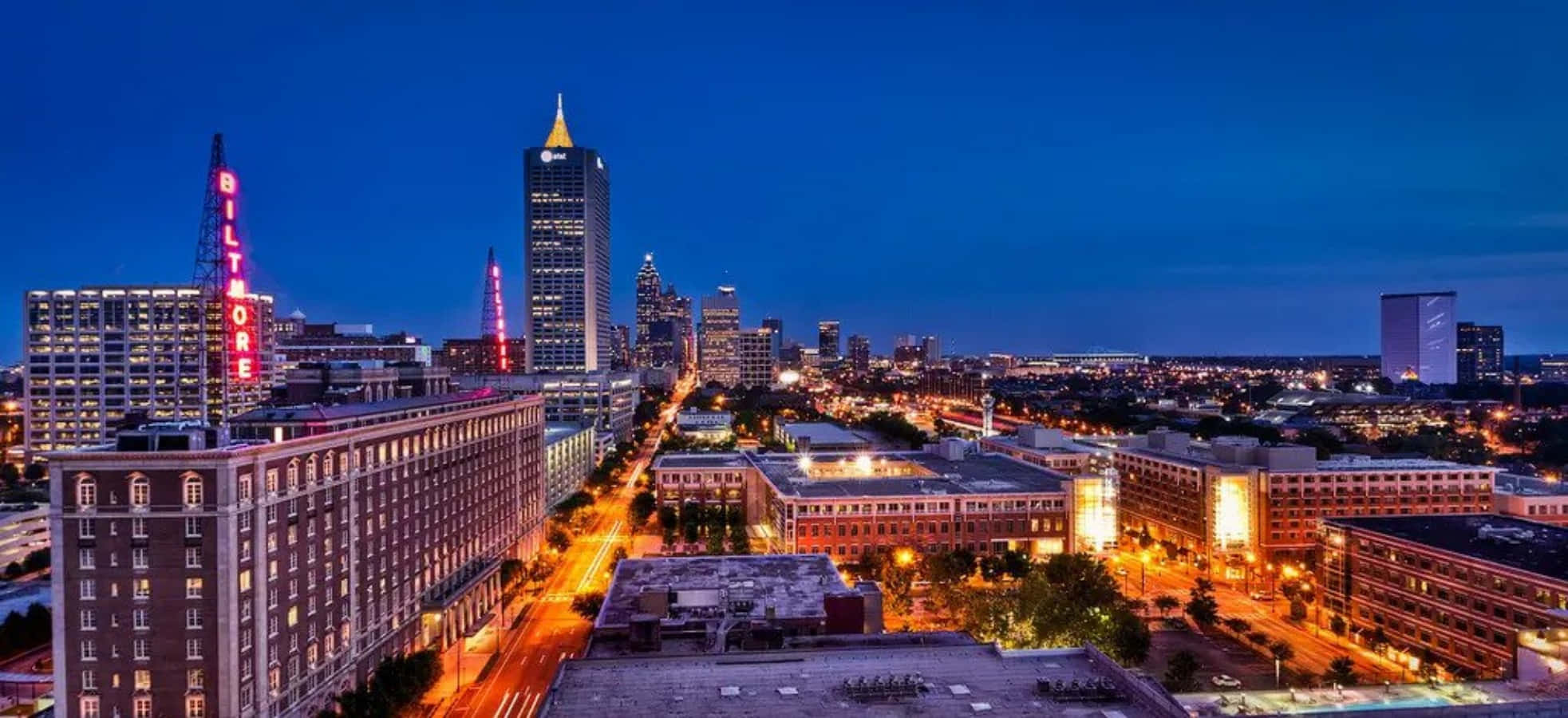 Atlanta Georgia 桌布 壁紙 — 深藍色天空下，黃昏時分充滿活力的城市景觀，摩天大樓燈火通明，街道閃爍發光。