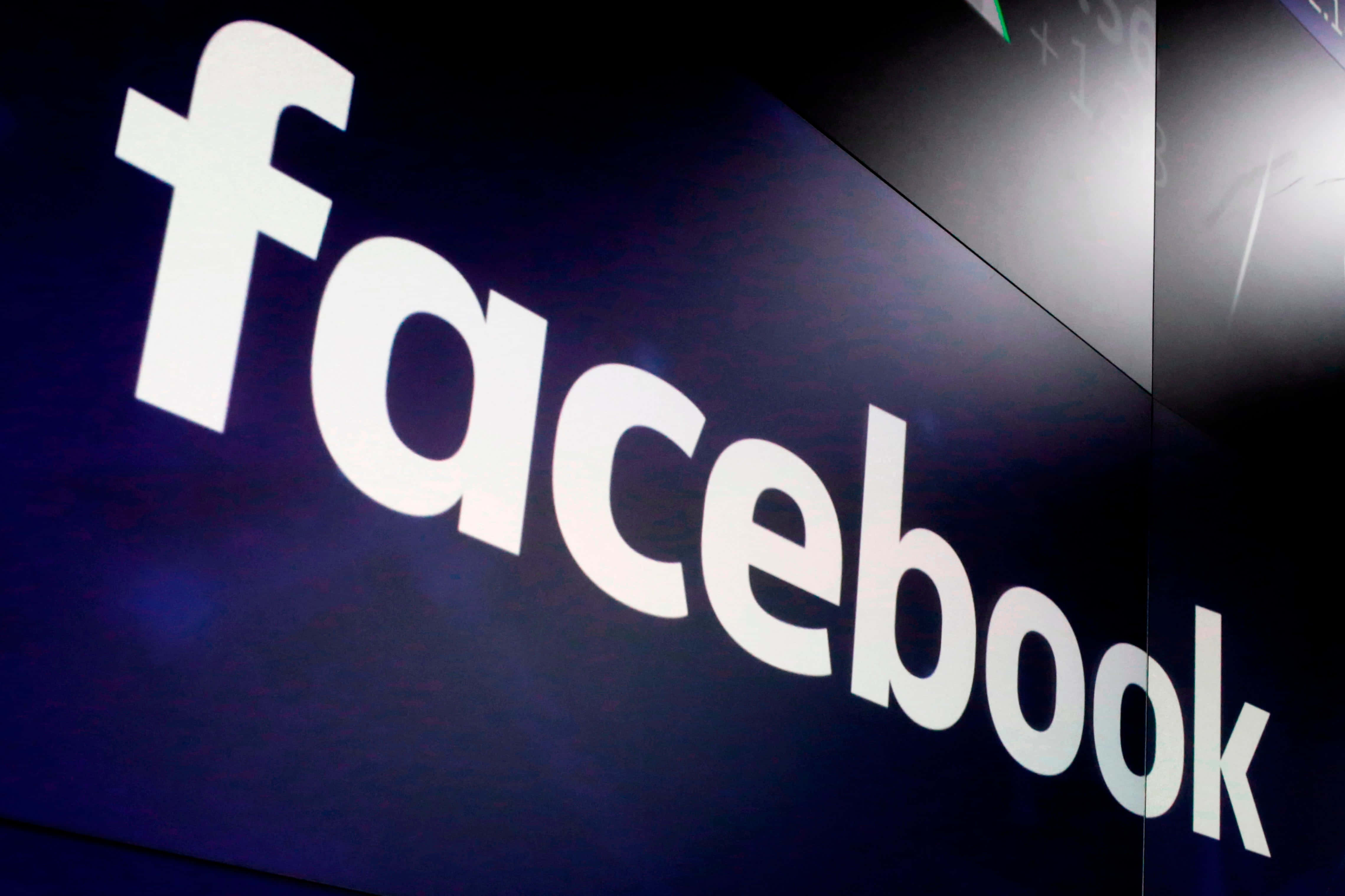 Facebook 桌布 壁紙 — 深藍色數位螢幕上發光的白色Facebook標誌特寫，背景有隱約的金融數據。