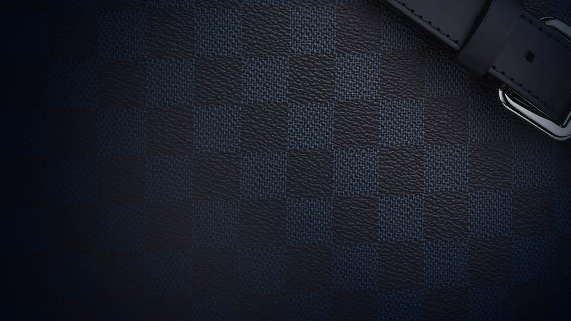 Louis Vuitton Pattern 桌布 壁紙 — 深藍色格紋皮革表面，右上角有黑色皮革錶帶和銀色扣環。