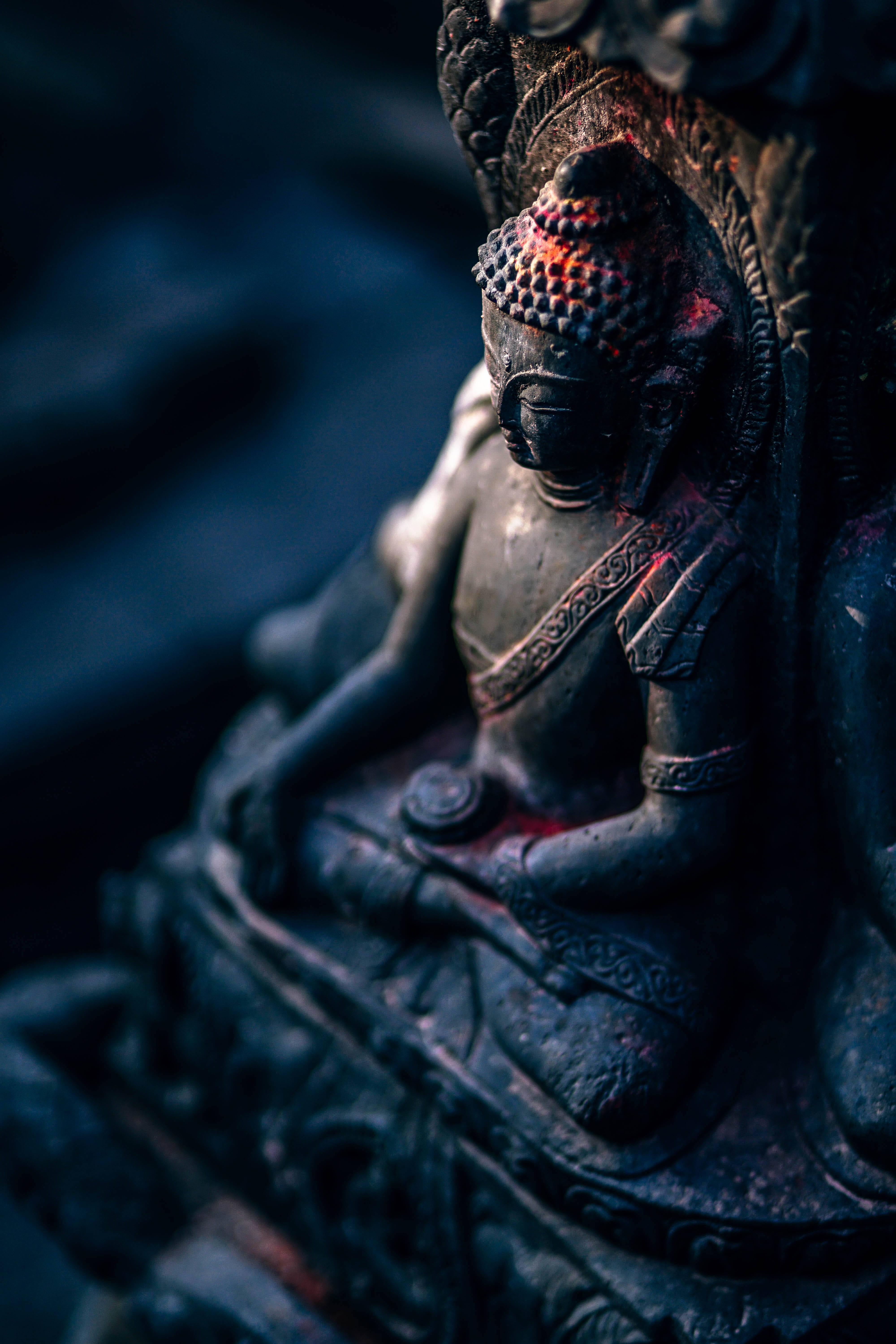 black buddha 桌布 壁紙 — 深藍色模糊背景下，一尊深色佛像頭部和肩部帶有發光紅色點綴的特寫。