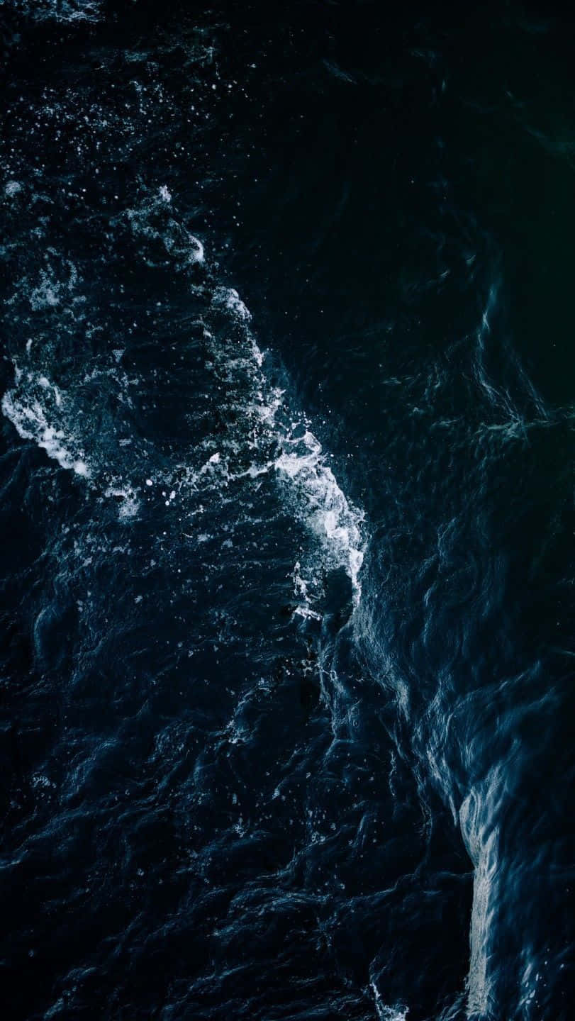 Dark Ocean 桌布 壁紙 — 深藍色海洋波浪拍打白色泡沫，撞擊在深色紋理海面上的鳥瞰圖。