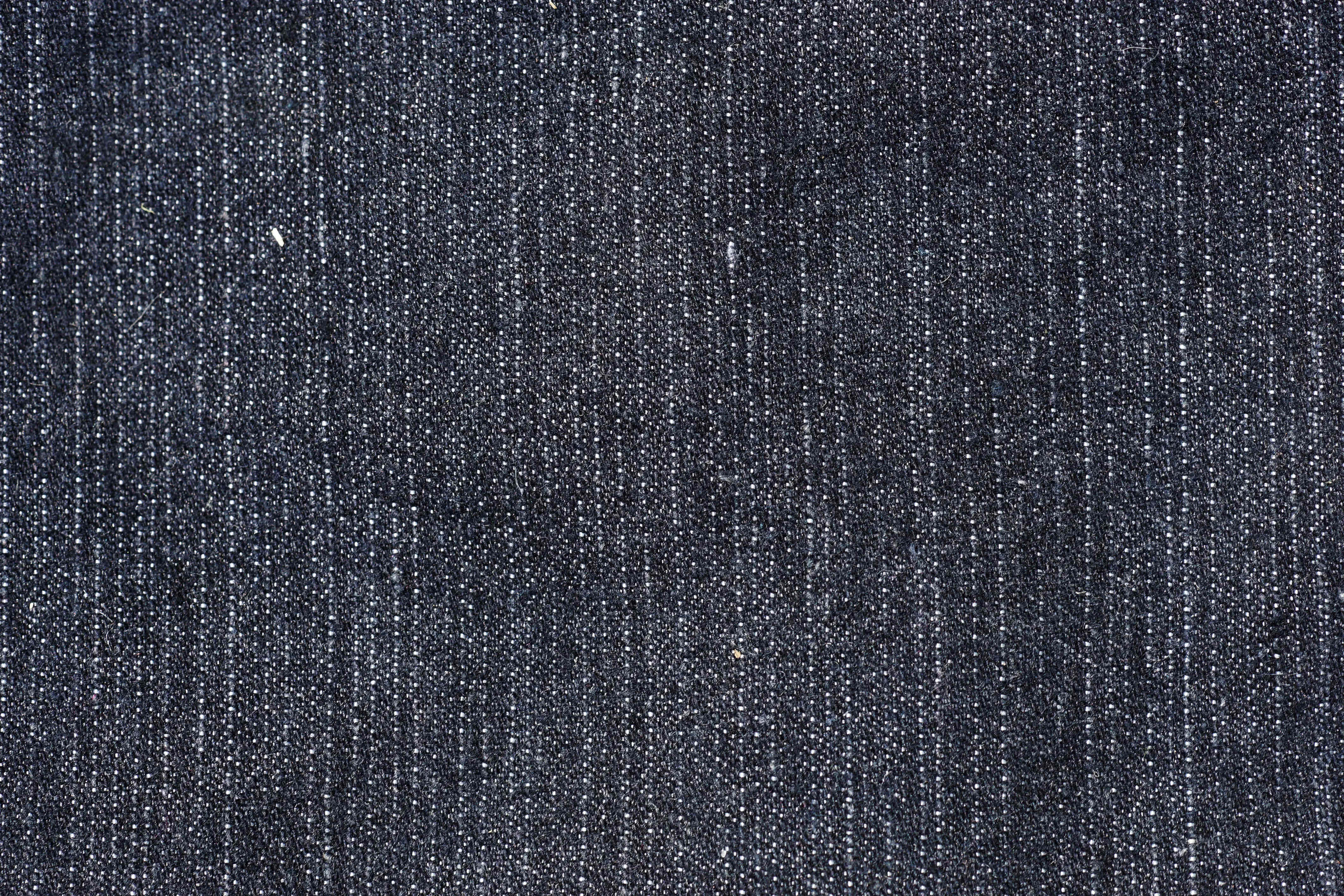 Denim 桌布 壁紙 — 深藍色牛仔布料的特寫，顯示出有紋理的編織和微妙的白色線條亮點。
