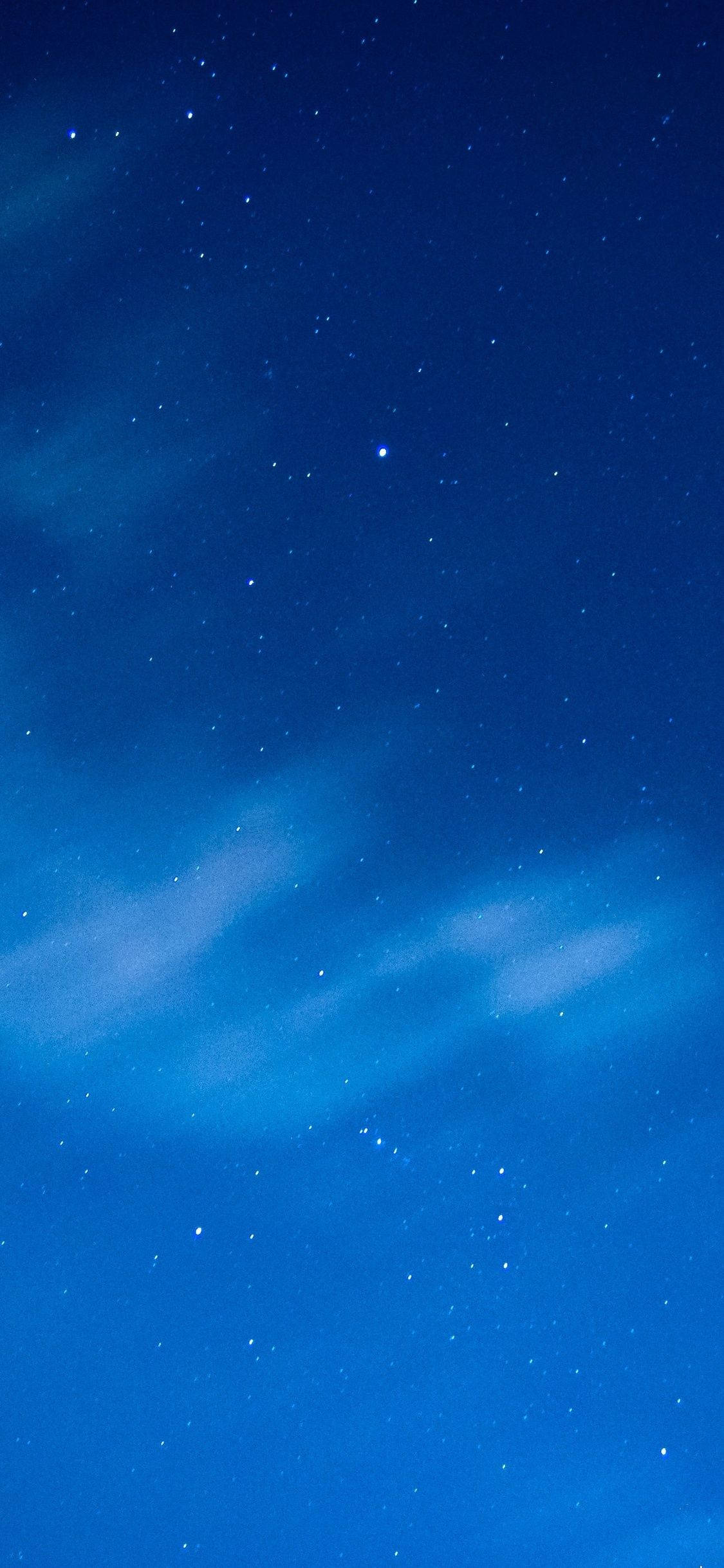 Blue iPhone 桌布 壁紙 — 深藍色的夜空佈滿閃爍的星星和飄過天際的縷縷薄雲。