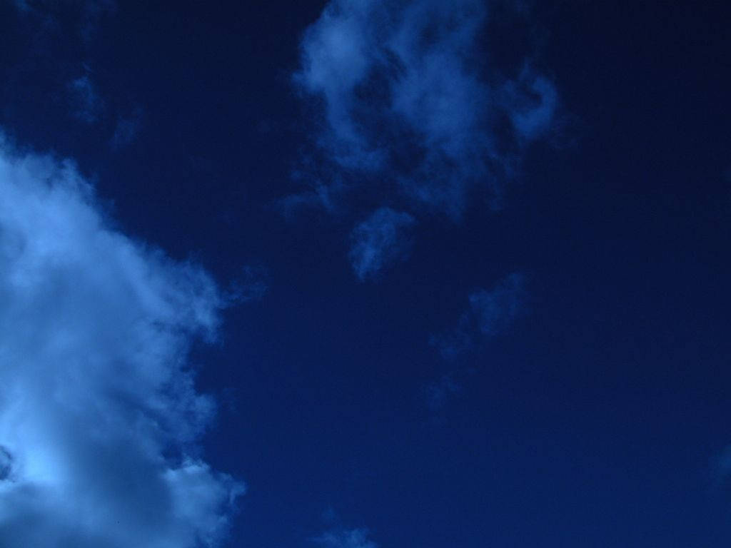 Indigo Aesthetic 桌布 壁紙 — 深藍色的暮色天空，有薄薄的雲在深靛藍色背景上柔和地發光。